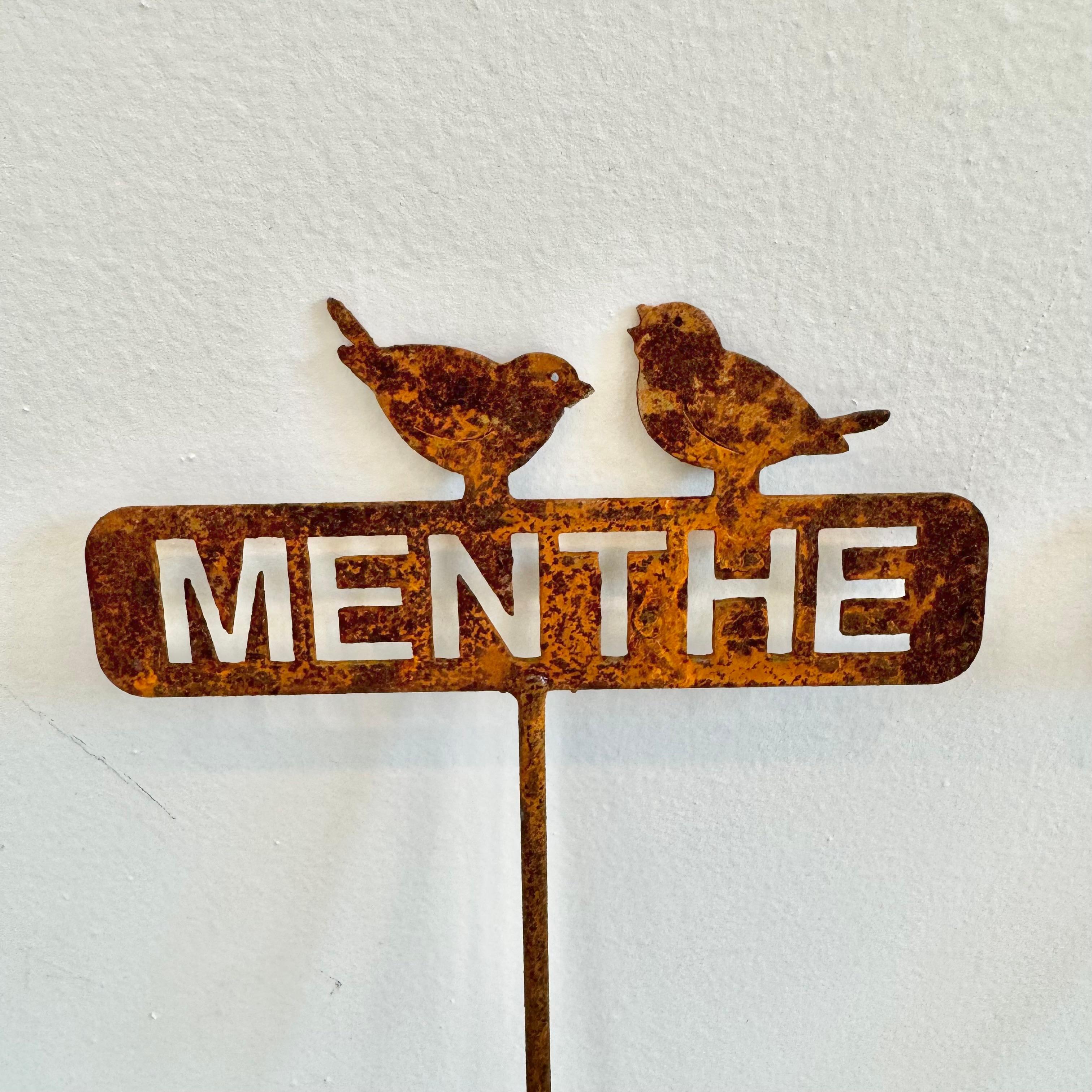 Long metal garden herb markers from France. Standing almost 2 feet tall. The head is a metal cutout of the name of the herb with 2 little birds perched on top. Heavy rusting gives the markers a beautiful dark brown/ orange color. The set contains :