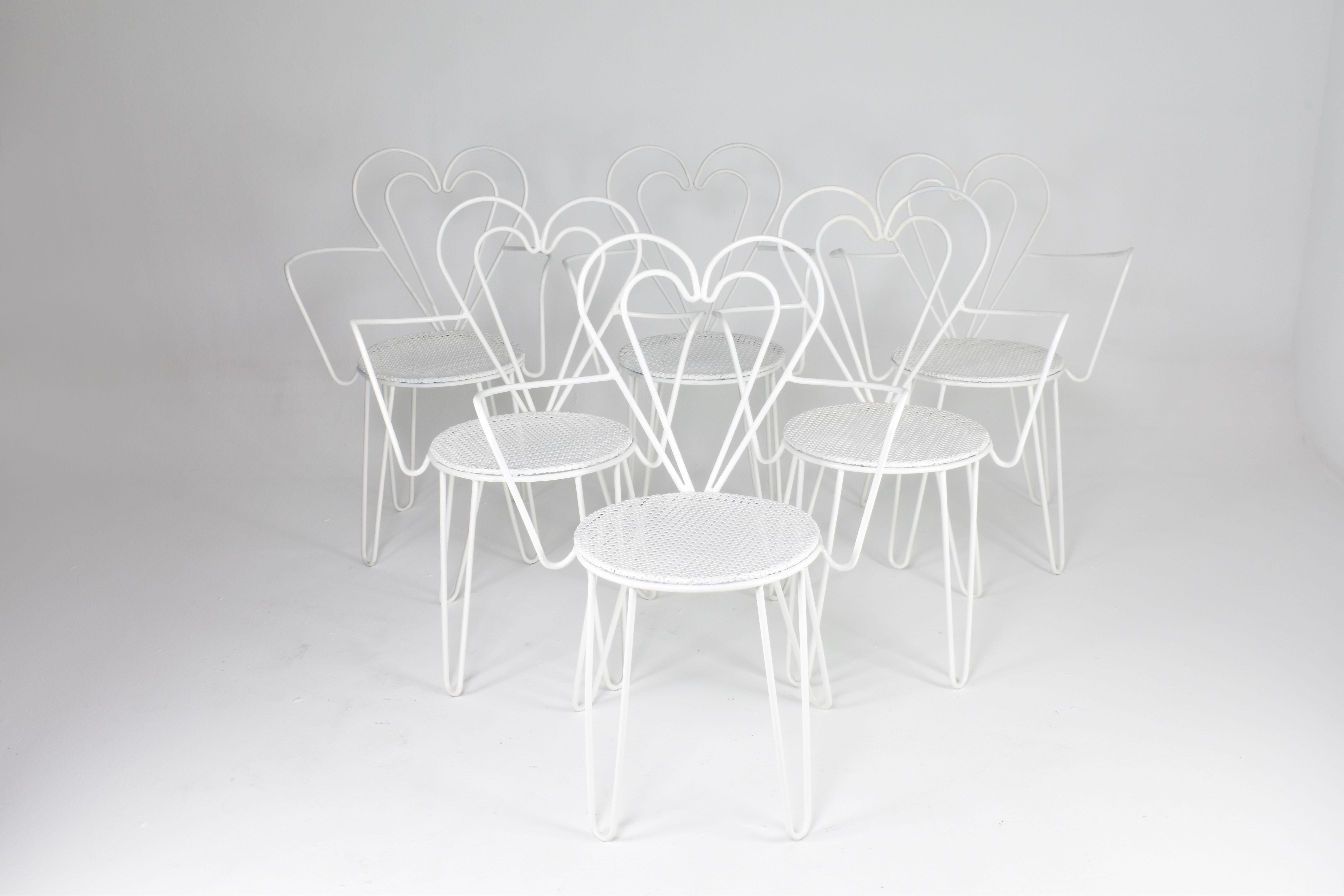 A set of six iconic chairs designed by the renowned Mathieu Matégot. These chairs are characterized by heart-shaped tubular steel frames, the famous perforated seat, and elegantly curved armrests. 

Mathieu Matégot, a prominent figure in mid-century