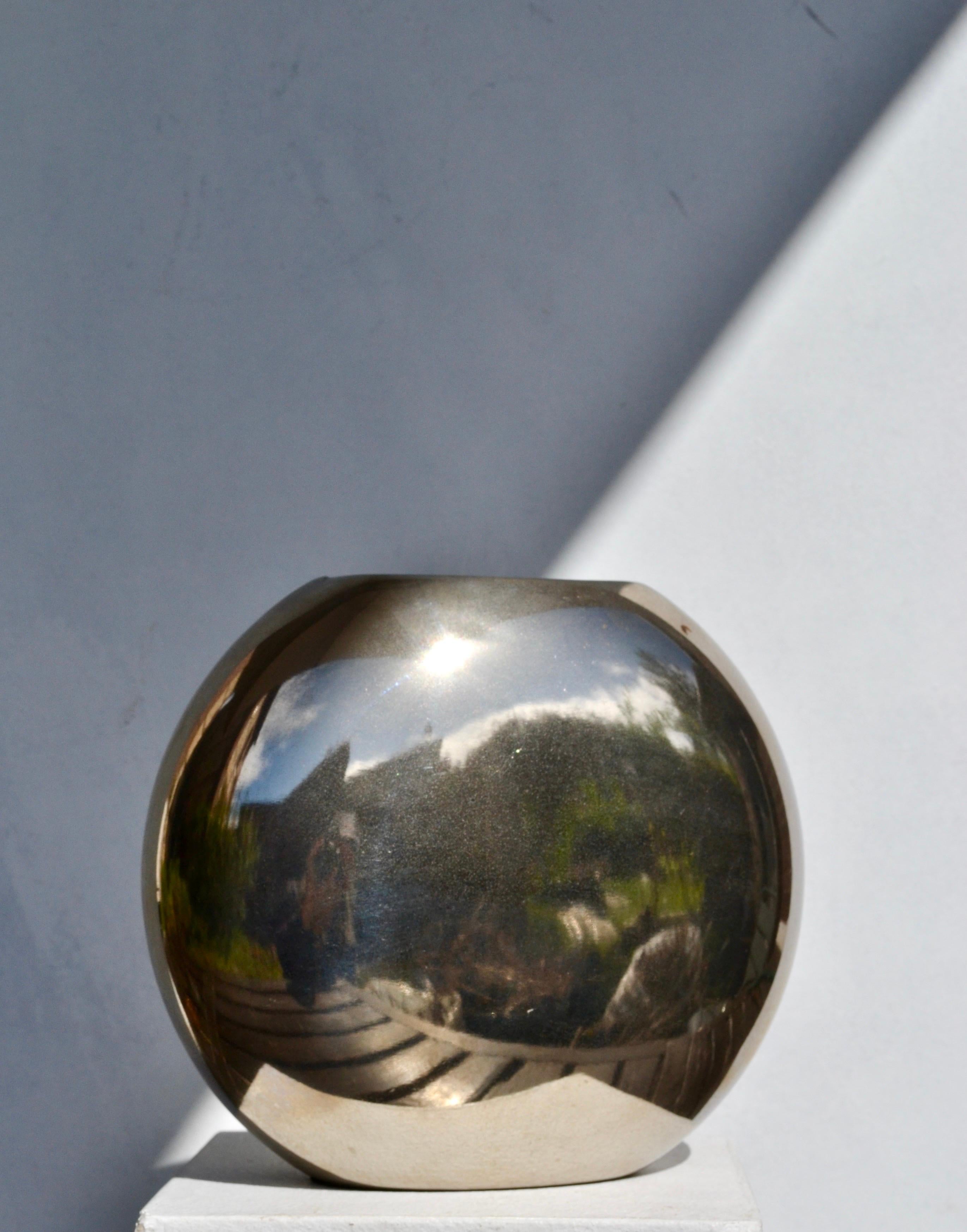 Sculptural vase in polished metal, France, 1970s.
Unusual lens-shaped form with a small opening at the top.
Minimalist design with a highly reflective surface, giving it a sculptural presence whether used as a vase or as a decorative object.

The