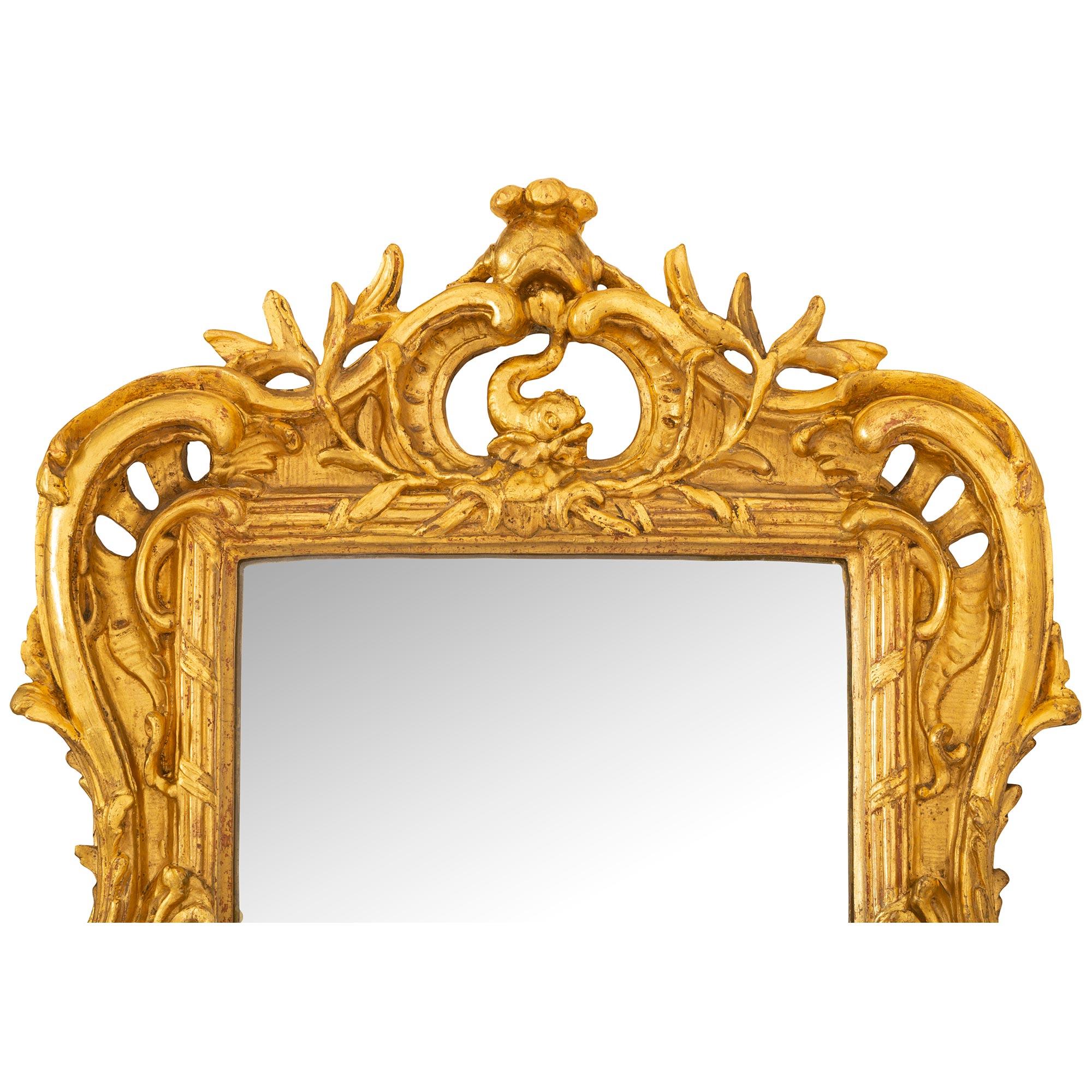 An exquisite and very high quality French mid 18th century Louis XV period giltwood mirror possibly created for Royal nobility. The beautiful small scale mirror retains its original mirror plate set within an elegant wraparound tied fluted border.