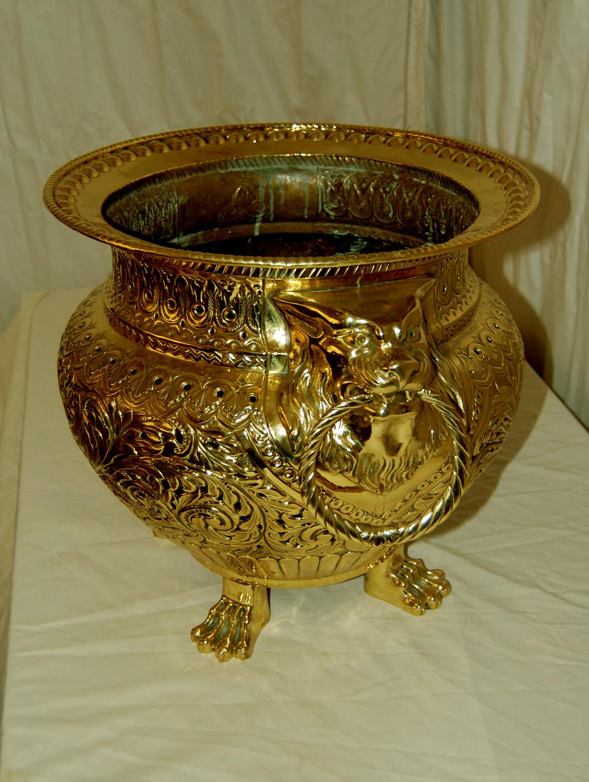 
 French brass pierced bold jardiniere with lion head holders for the ring handles and four paw feet.  This large exceptional jardiniere is chased, engraved and pierced with an elegant shape that is made for good sized plants. The brass is