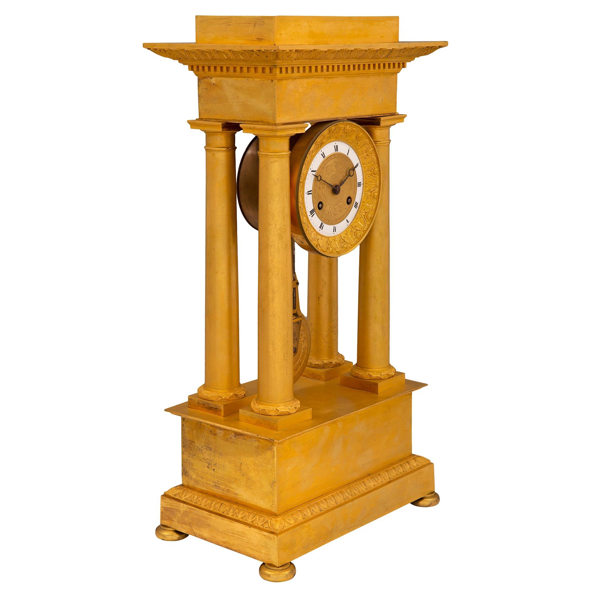 An exceptional French mid 19th century Charles X period ormolu portico clock. The clock is raised by fine bun feet below the rectangular base with an elegant mottled design and richly chased wrap around Coeur de Rai band. At the center are four