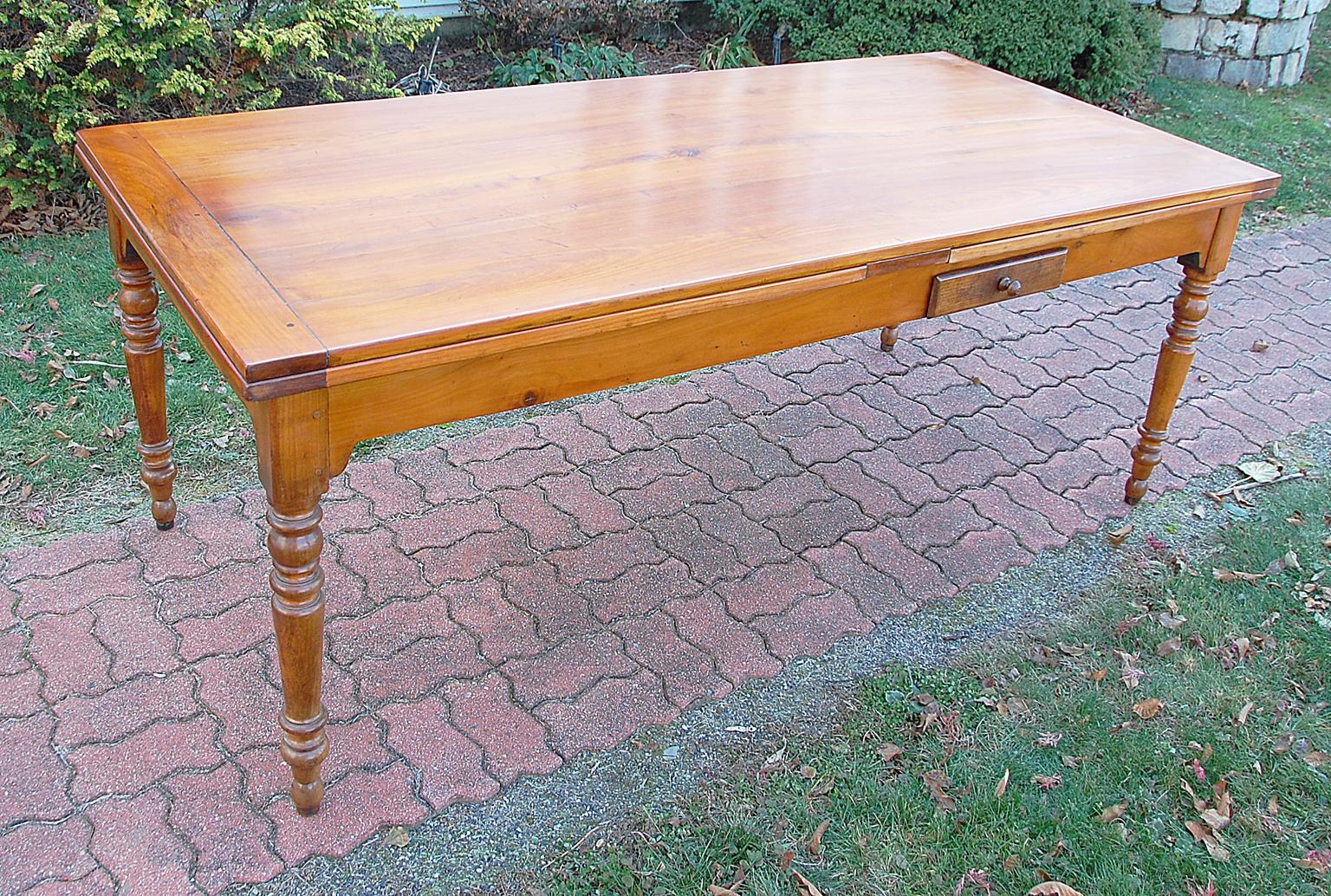 French cherry farmhouse extending table of the mid-19th century with turned legs and two pullout extensions which are chestnut bordered by cherry. The turned legs have been ended out about an inch, the rails that extend the top sections have been