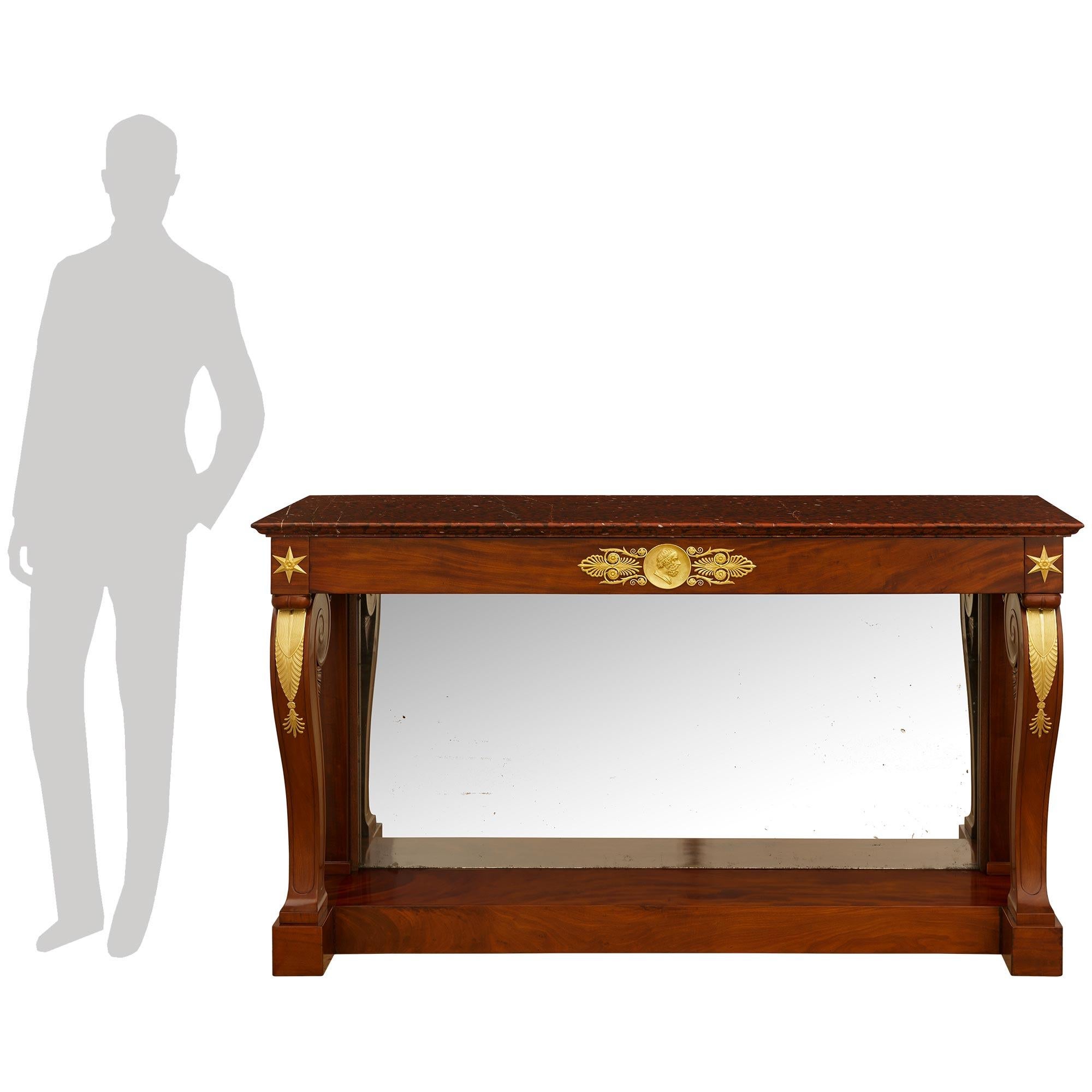 Preciosa consola francesa de alta calidad de mediados del siglo XIX, de estilo Imperio, de caoba, ormolu y mármol Rouge Griotte. Esta maravillosa consola independiente se eleva sobre una base cuadrada de bloques de caoba flameada, con los soportes