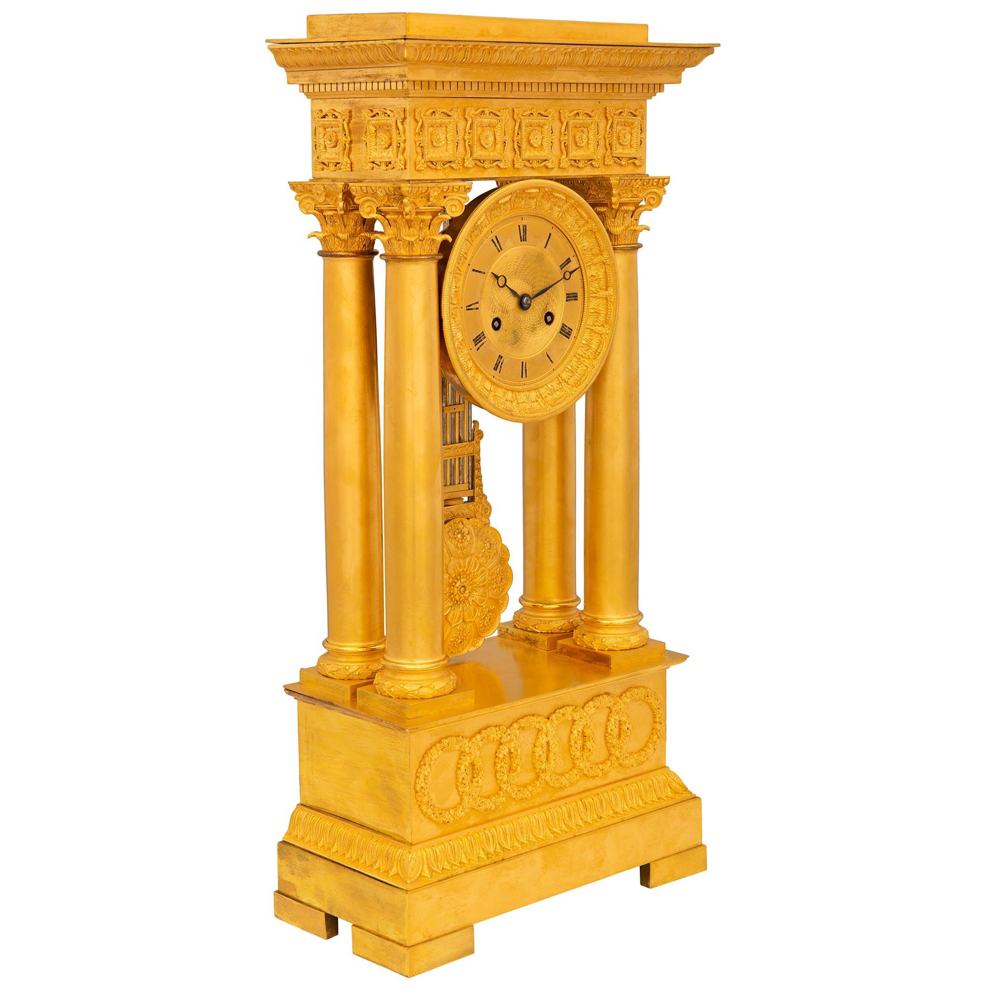 Une exquise horloge portique française du milieu du 19ème siècle, de style Empire en bronze doré. L'horloge repose sur une base rectangulaire avec des bordures finement ciselées et des cercles imbriqués satinés et brunis. Au-dessus se trouvent