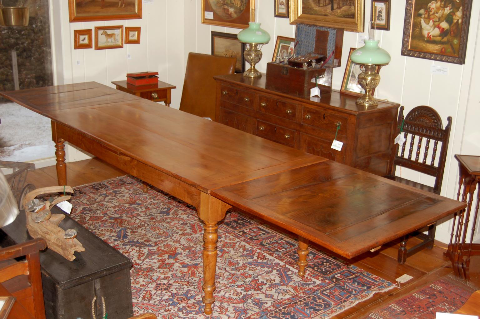 French Provincial cherry and chestnut extending farmhouse table of the mid 19th century. The table is 78 1/2 inches long but hidden under the table top are two leaves that pullout and extend the length to either 113