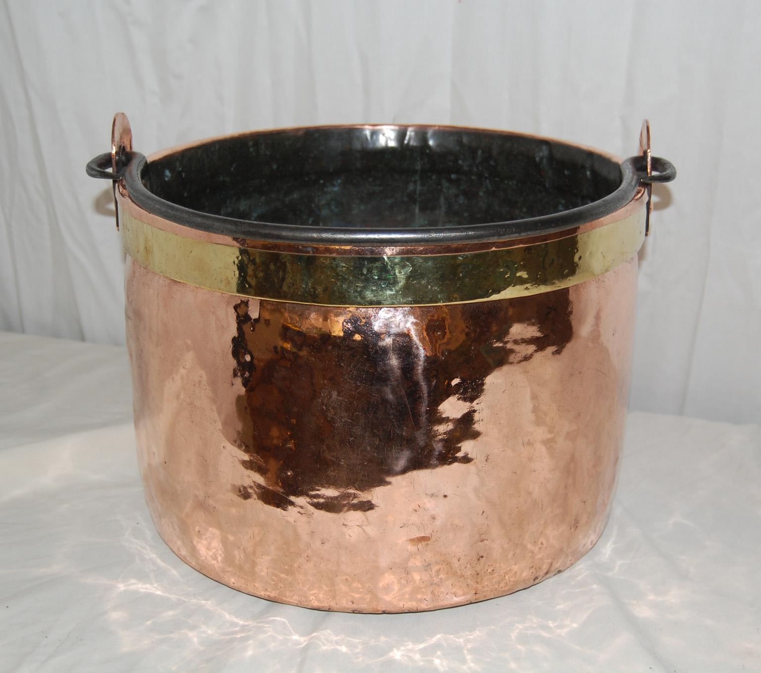 

  French mid 19th century large copper cauldron with brass rim.  This very heavy duty dovetailed cauldron has an iron swing handle and a thick band of brass just under the rim on the outside.  The French quite often reinforced these large kettles