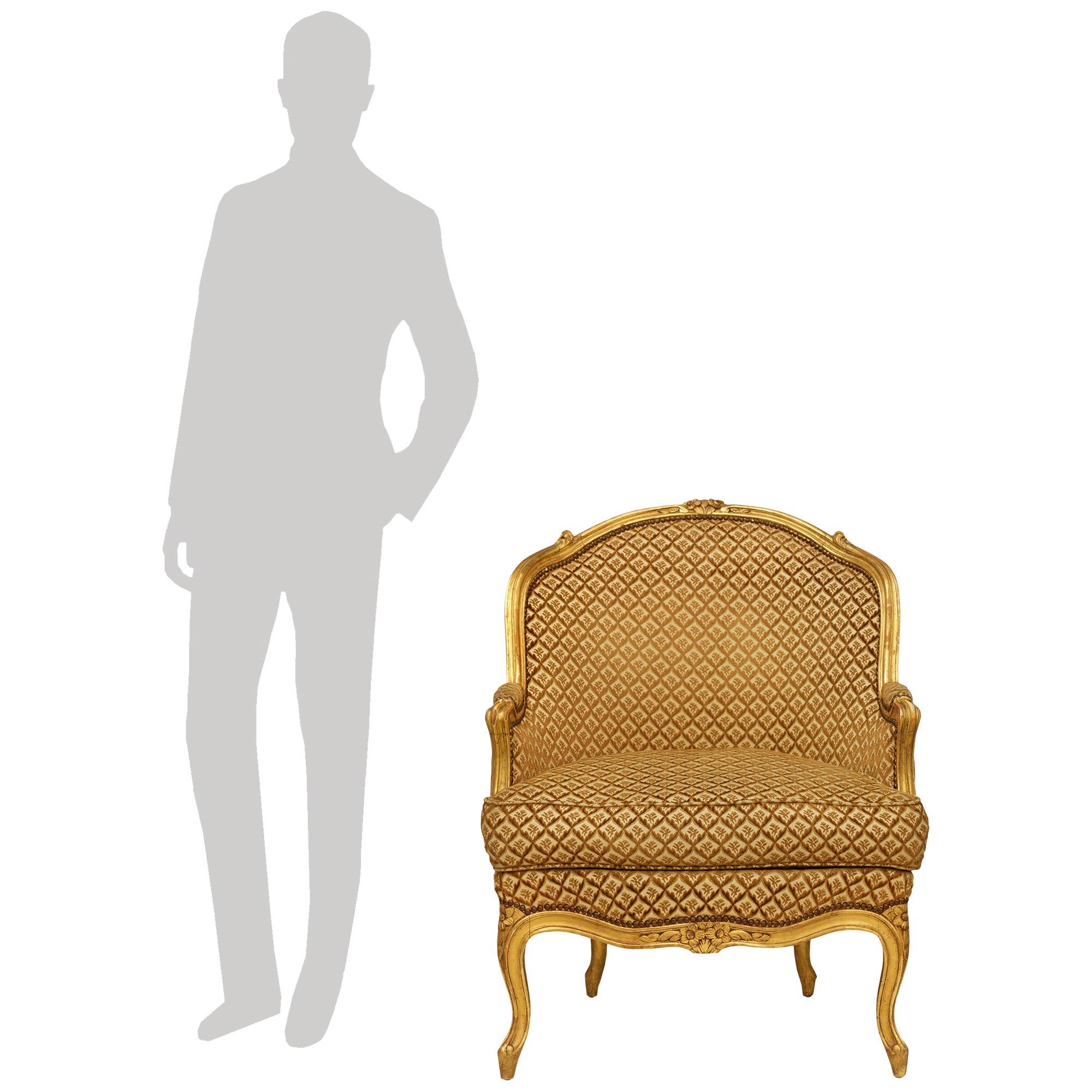 Un'elegante poltrona francese di alta qualità della metà del XIX secolo, in stile Luigi XV, in legno dorato Bergère. Questa meravigliosa sedia è sollevata su quattro gambe cabriole in legno d'orato con disegni screziati che conducono a fiori