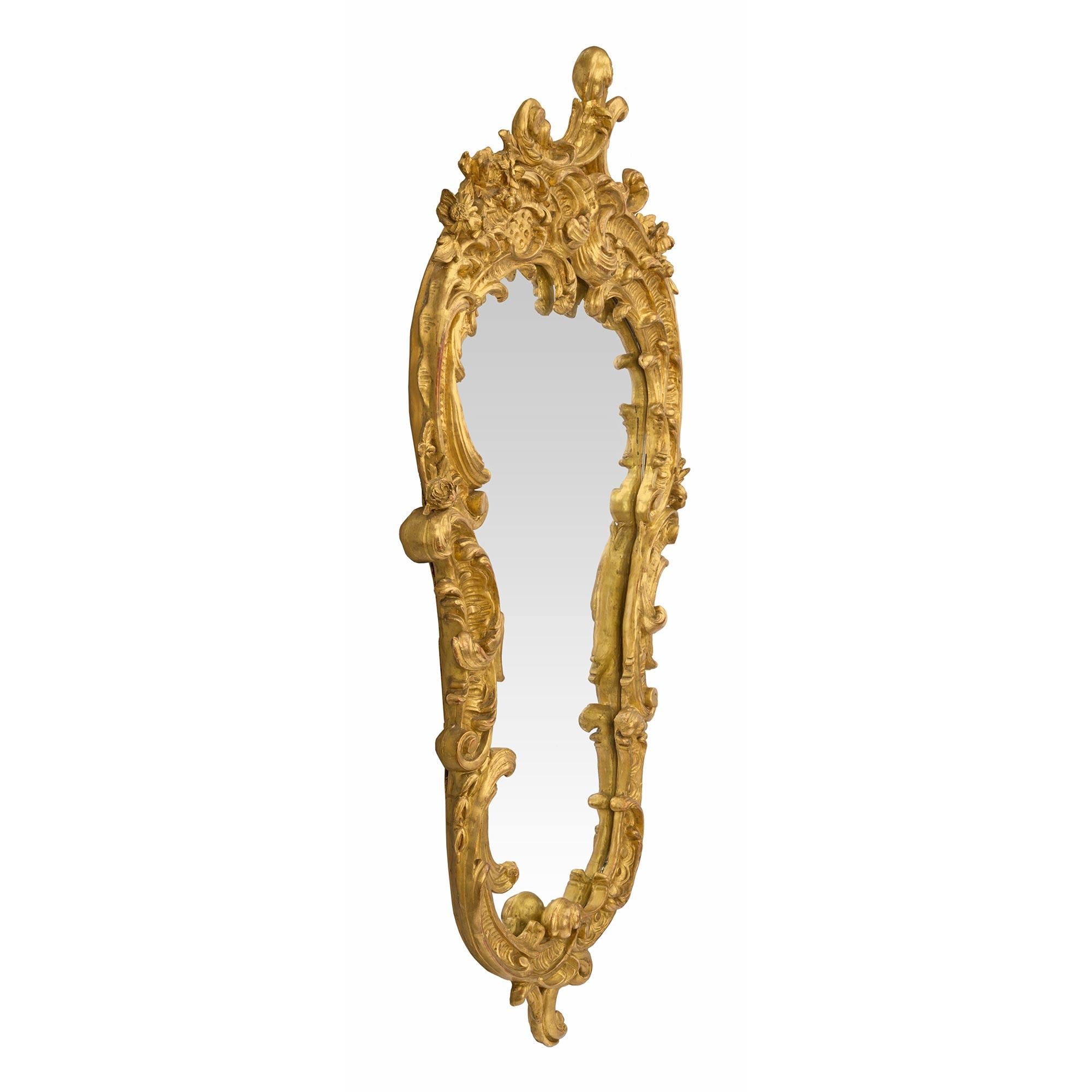 A beautiful French mid 19th century Louis XV st. giltwood mirror. The mirror plate is framed within a most decorative curvaceous giltwood border. At the base is a striking scrolled movement with elegant richly carved foliate designs. The designs