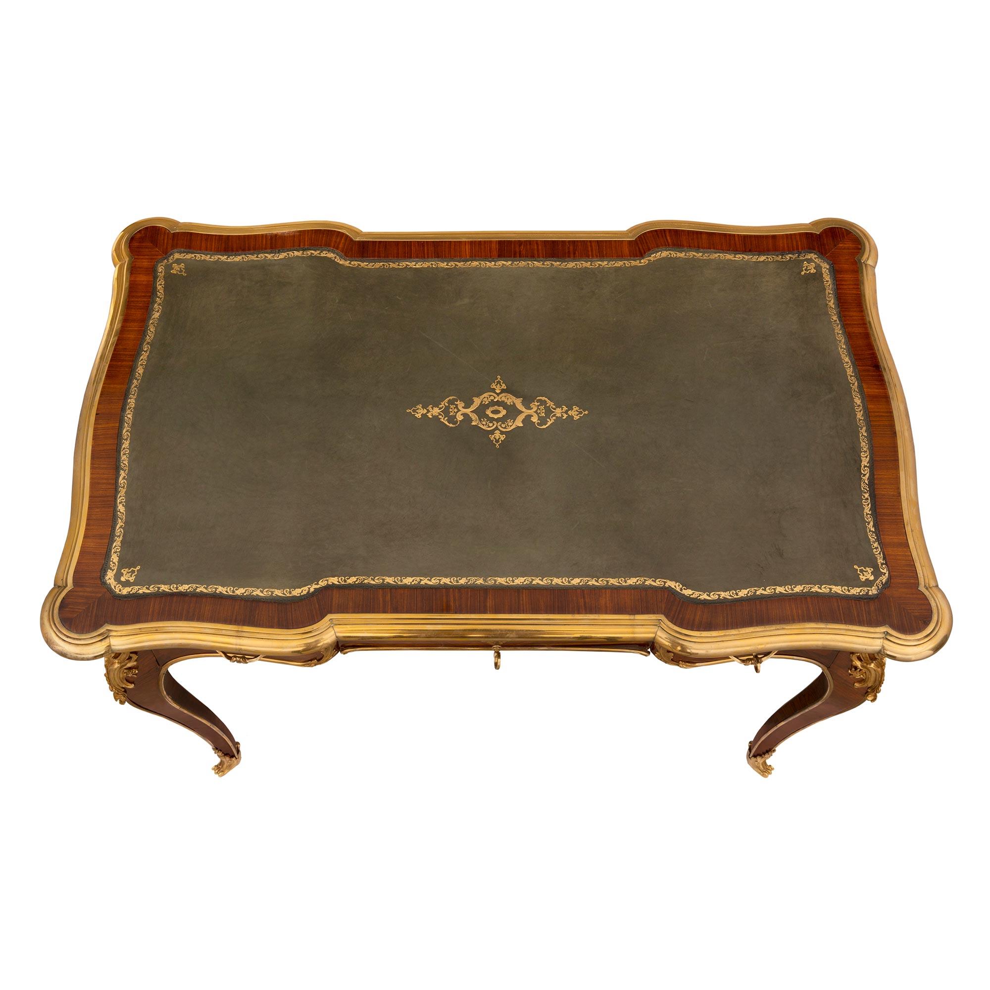 Magnifique bureau plat de style Louis XV du milieu du XIXe siècle, en bois royal et bronze doré. Le bureau est surélevé par d'élégants pieds cabriole avec des sabots en bronze doré finement ajustés et enveloppés d'un joli motif feuillagé. De