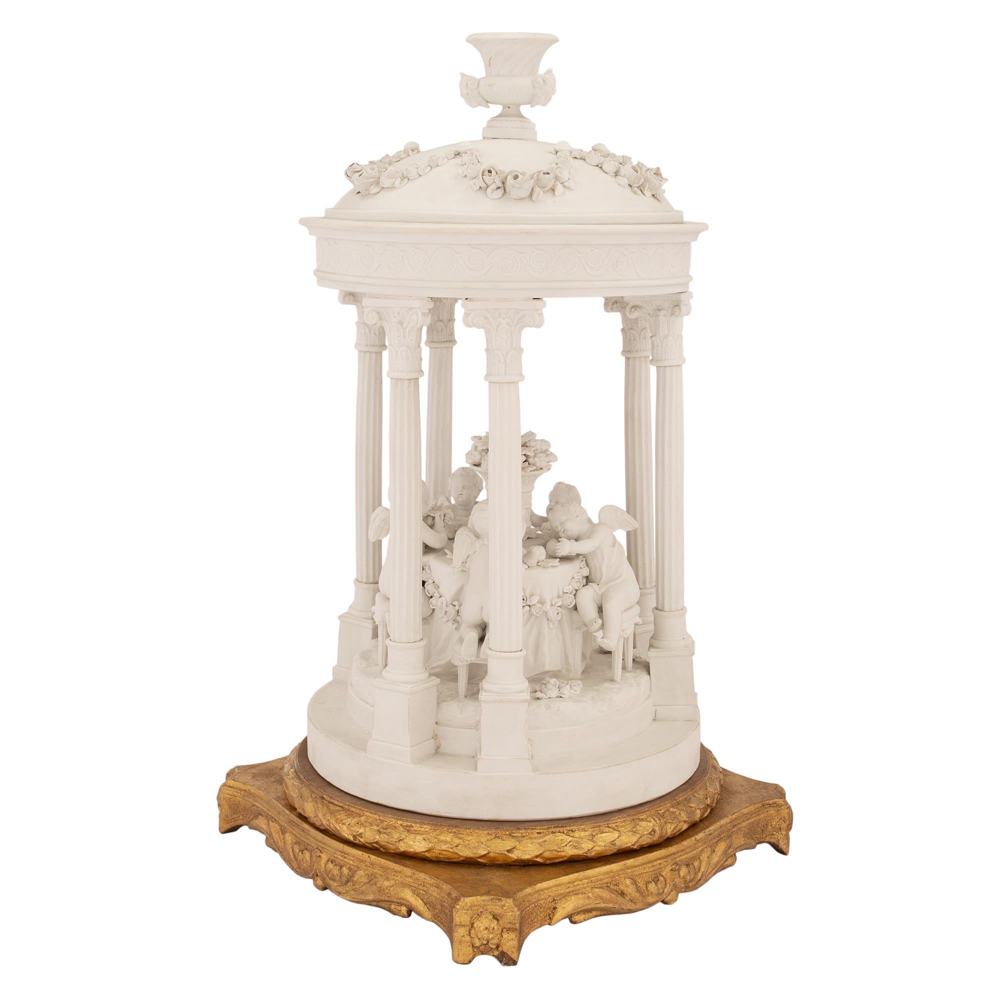A sensational French mid 19th century Louis XVI st. Biscuit de Sèvres and giltwood centerpiece. The statue is raised by a richly detailed square giltwood base with slightly curved sides. Each side are decorated scrolled acanthus leaves below a fine