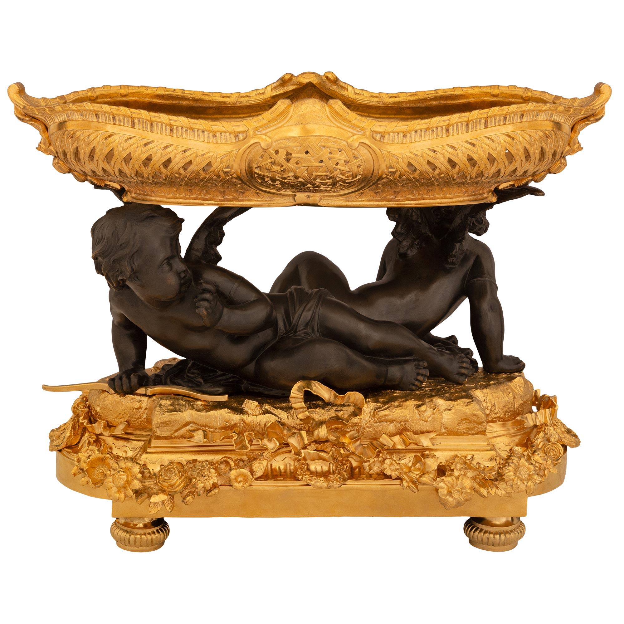 A sensational and large scaled French mid 19th century Louis XVI st. Ormolu and patinated Bronze centerpiece. The centerpiece is raised by topie shaped feet below a richly decorated base. The base has a central bow with a swaging floral garland.