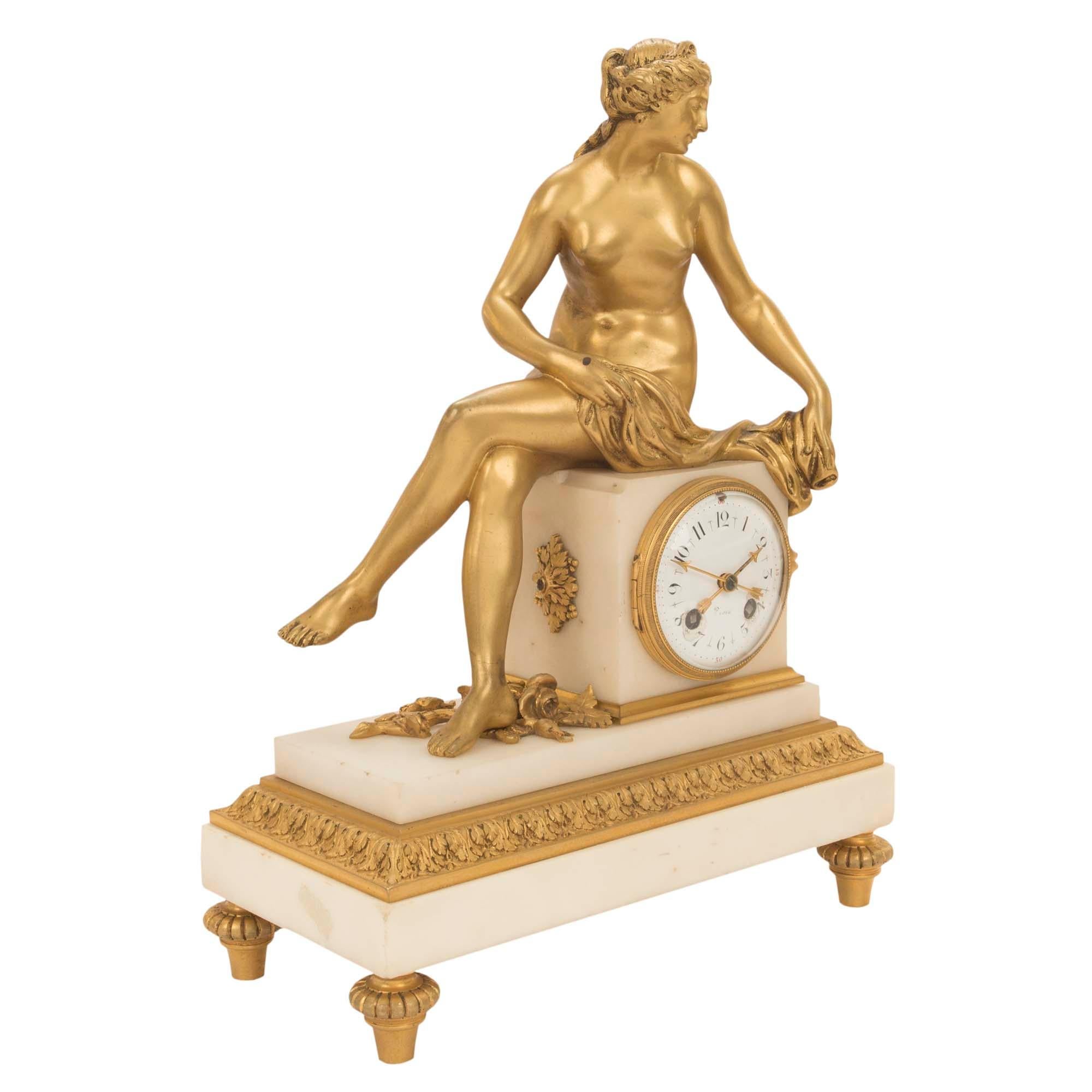 Une très belle pendule française du milieu du 19ème siècle, de style Louis XVI, en bronze doré et marbre blanc de Carrare. La pendule est surélevée par des supports en bronze doré en forme de topie. La base rectangulaire en marbre est décorée d'une