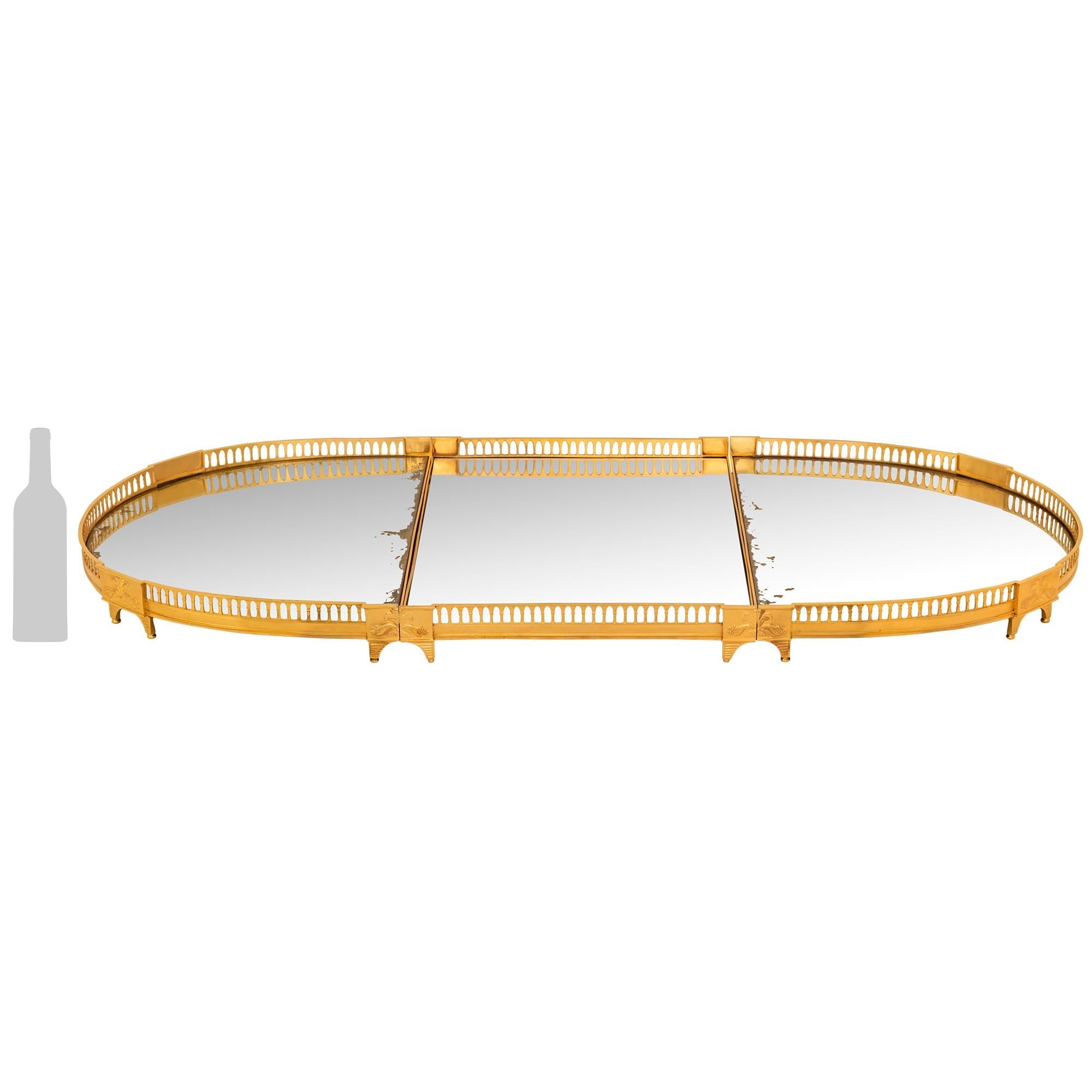 An impressive and high quality French mid 19th century Louis XVI st. Ormolu centerpiece plateau. The three piece centerpiece, with all original mirror plates, is raised by curved reeded supports below block reserves adorned with cornucopias. A