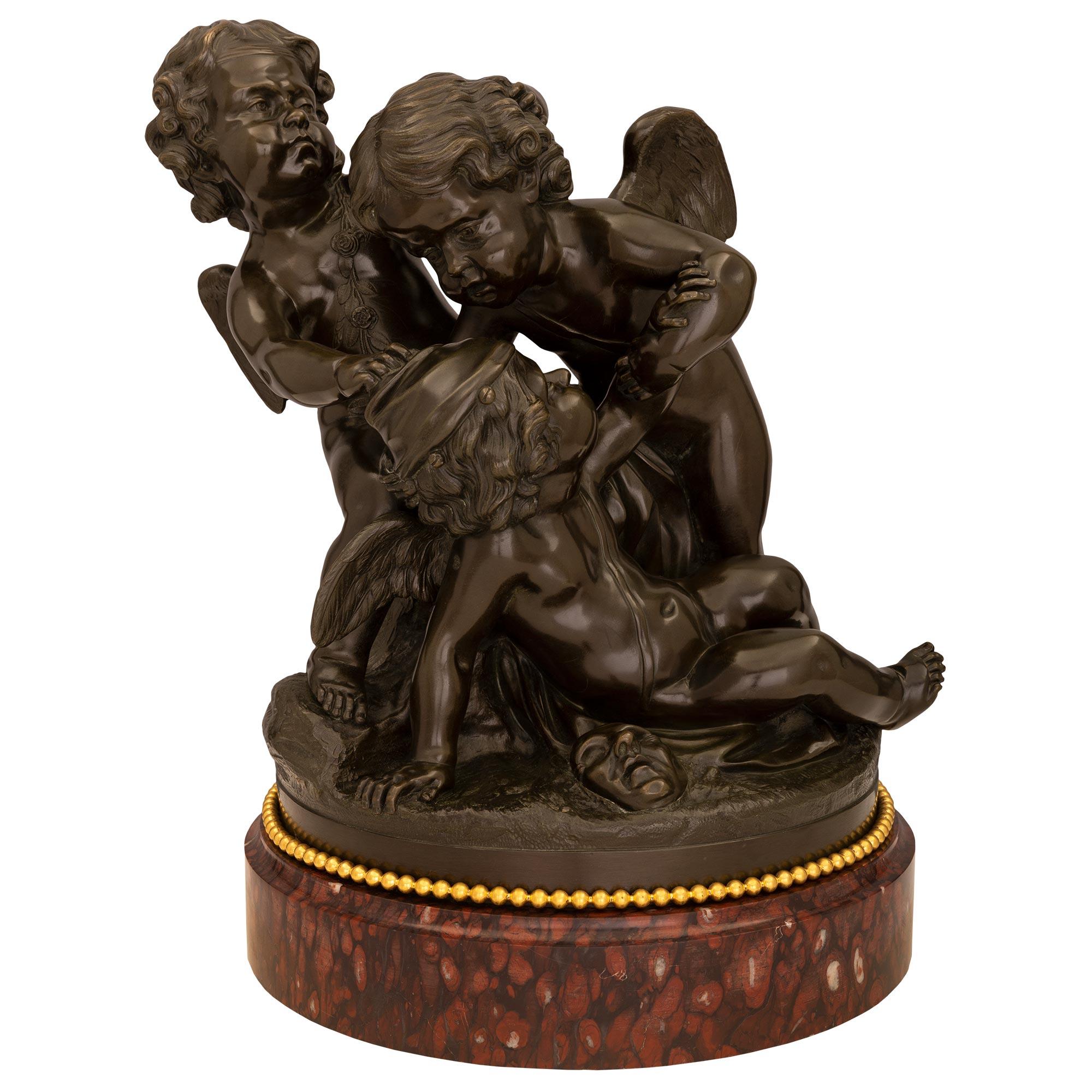 Charmante statue française du milieu du XIXe siècle, de style Louis XVI, en bronze patiné, bronze doré et marbre, d'après Clodion. La statue est surélevée par un épais socle en marbre Rouge Griotte décoré d'une bande perlée en bronze doré. Le bronze