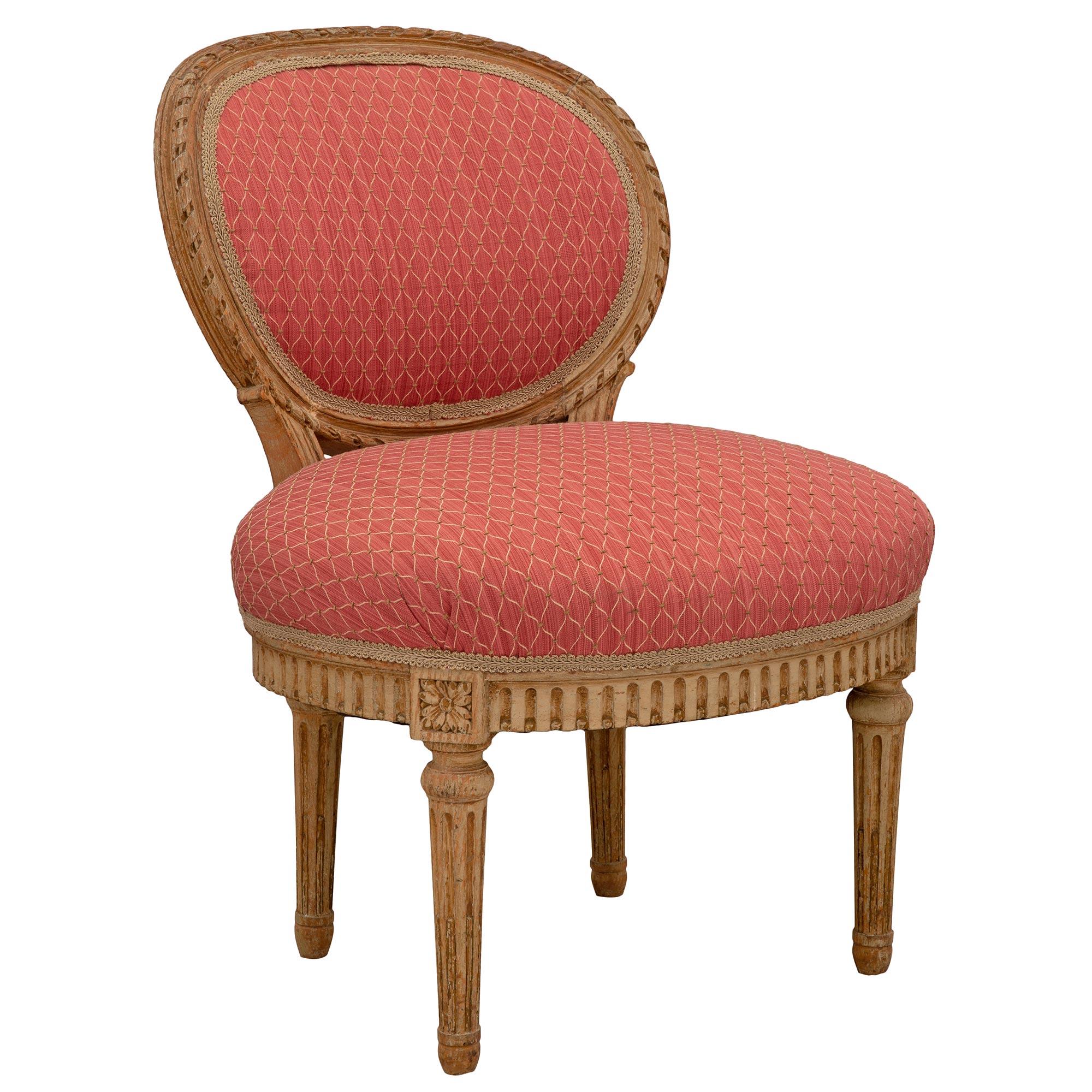 Charmante chaise d'enfant française du milieu du 19e siècle en bois patiné de style Louis XVI. La chaise est surélevée par d'élégants pieds circulaires fuselés et cannelés sous des rosettes richement ciselées. Le tablier présente un motif cannelé