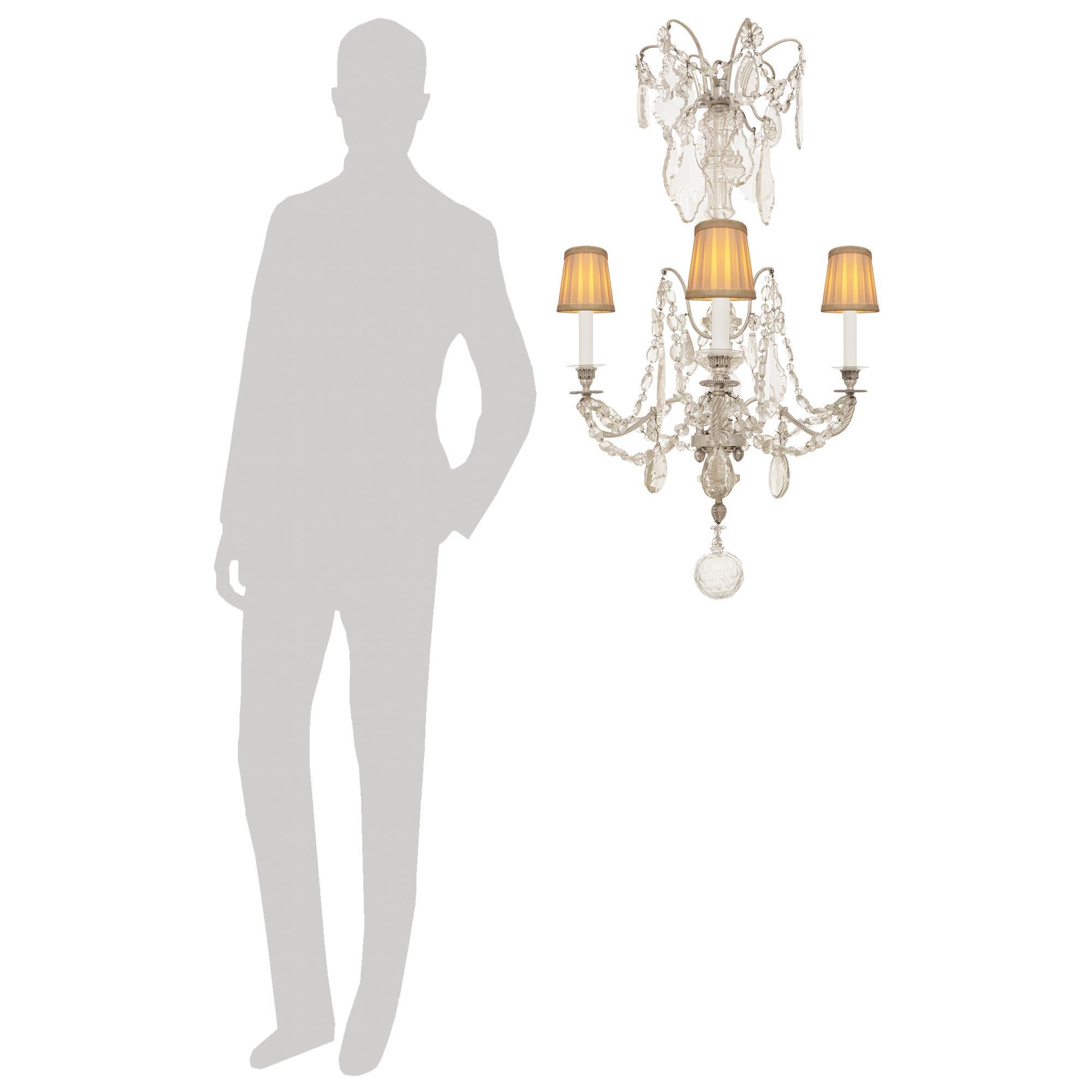Un elegante e unico lampadario francese della metà del XIX secolo in bronzo argentato e cristallo Baccarat. Questo splendido lampadario a tre luci è centrato in basso da una sfera di cristallo Baccarat sfaccettata di grandi dimensioni. Sopra ci sono