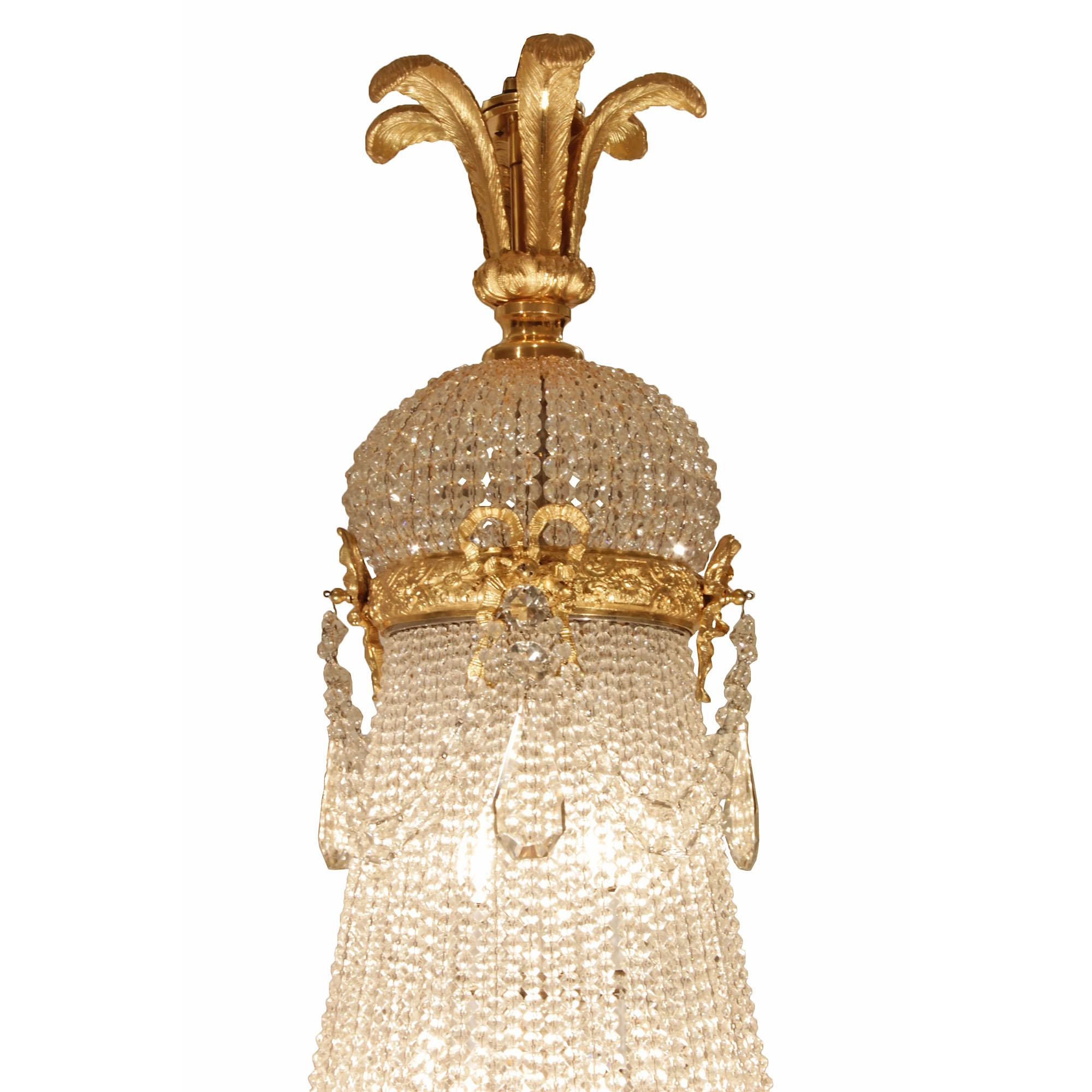 A grand French mid 19th century Louis XVI st. Baccarat crystal and ormolu chandelier. At the bottom is an ormolu acanthus leaf inverted finial with ormolu crown with kite shaped crystal pendants. Above are strands of graduating crystal garlands,