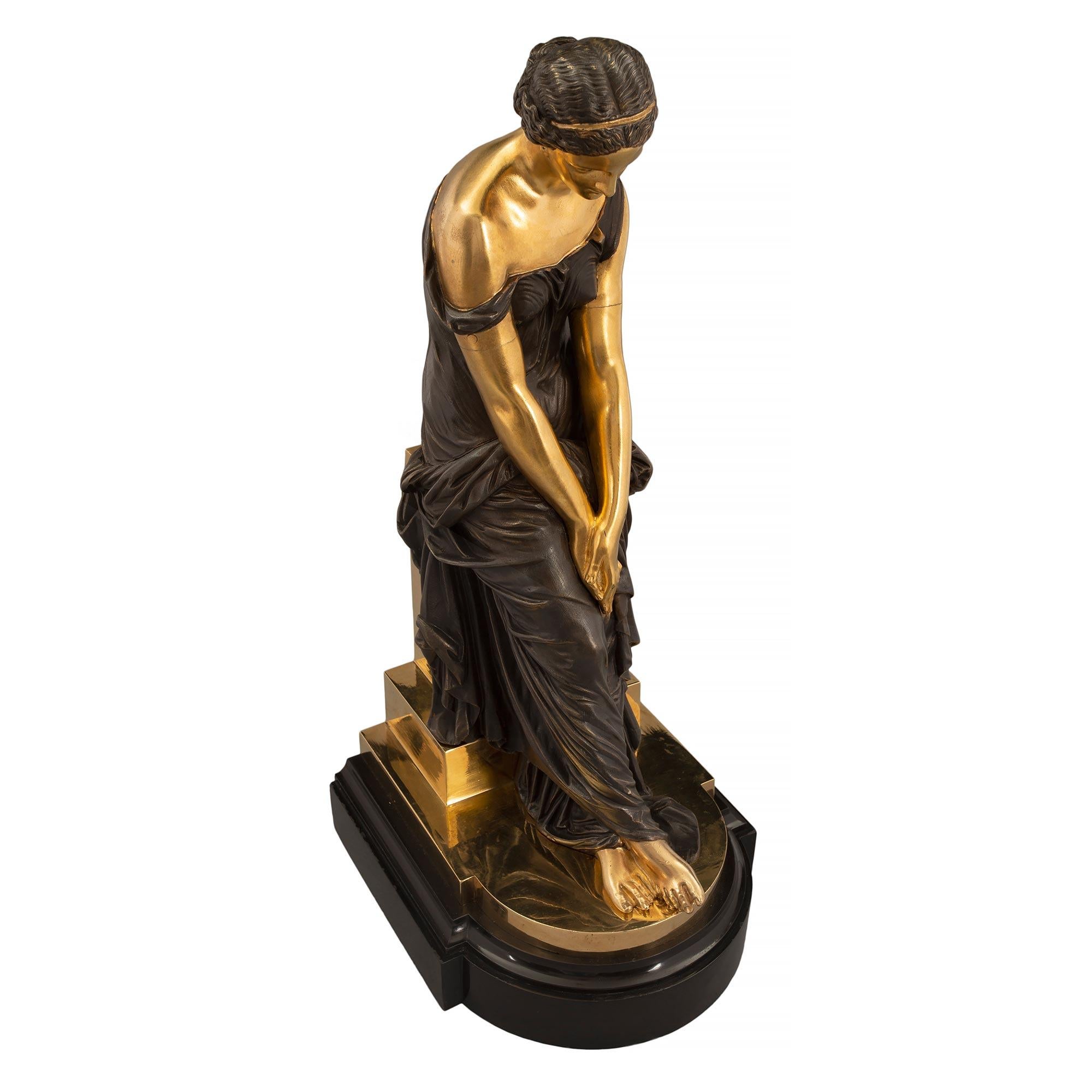 An elegant French mid 19th century Louis XVI st. patinated bronze and ormolu statue of a maiden, signed by Alexander Schoenwerck. The bronze is raised by an impressive Black Belgium marble mottled base with a rounded front. Above is the maiden, in