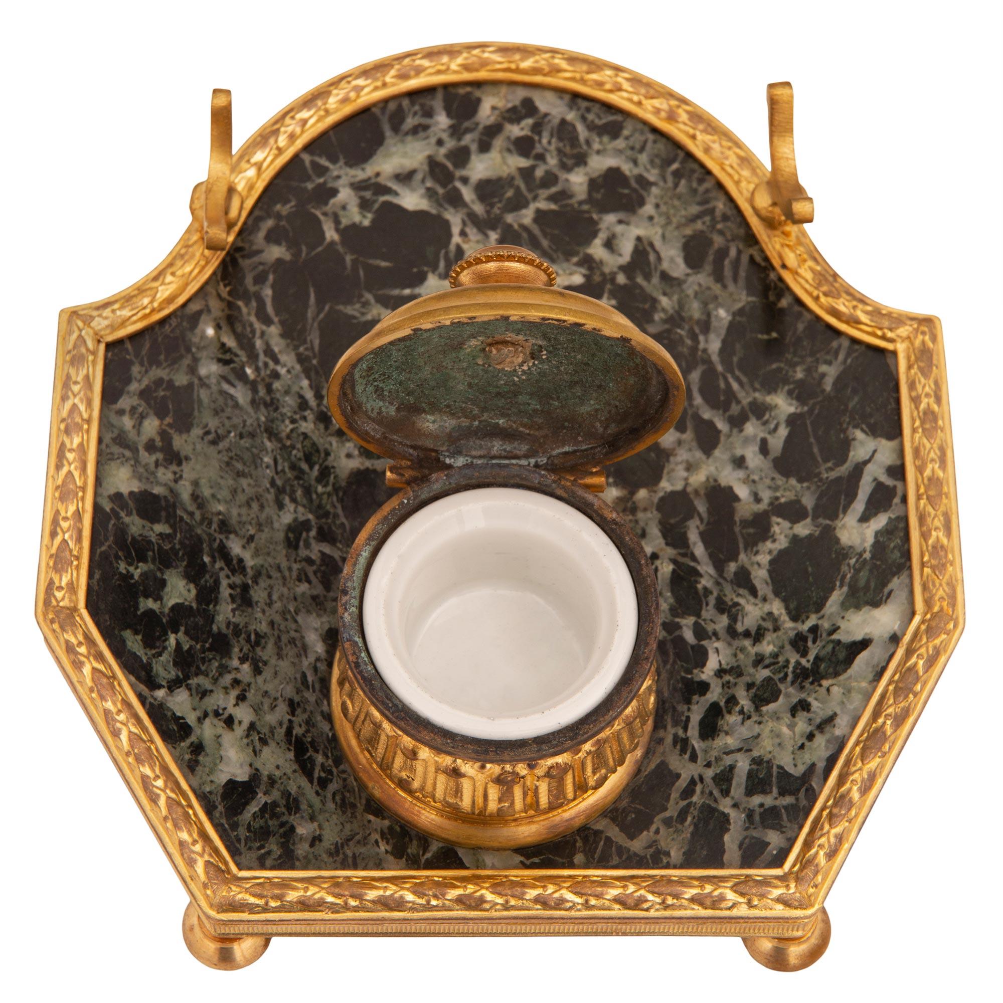 An elegant and charming French 19th century Louis XVI st. ormolu and Vert de Patricia marble inkwell. The inkwell is raised by Fine topie shaped feet below the elegantly shaped wrap around ormolu band with a fluted, berried laurel and beaded design.