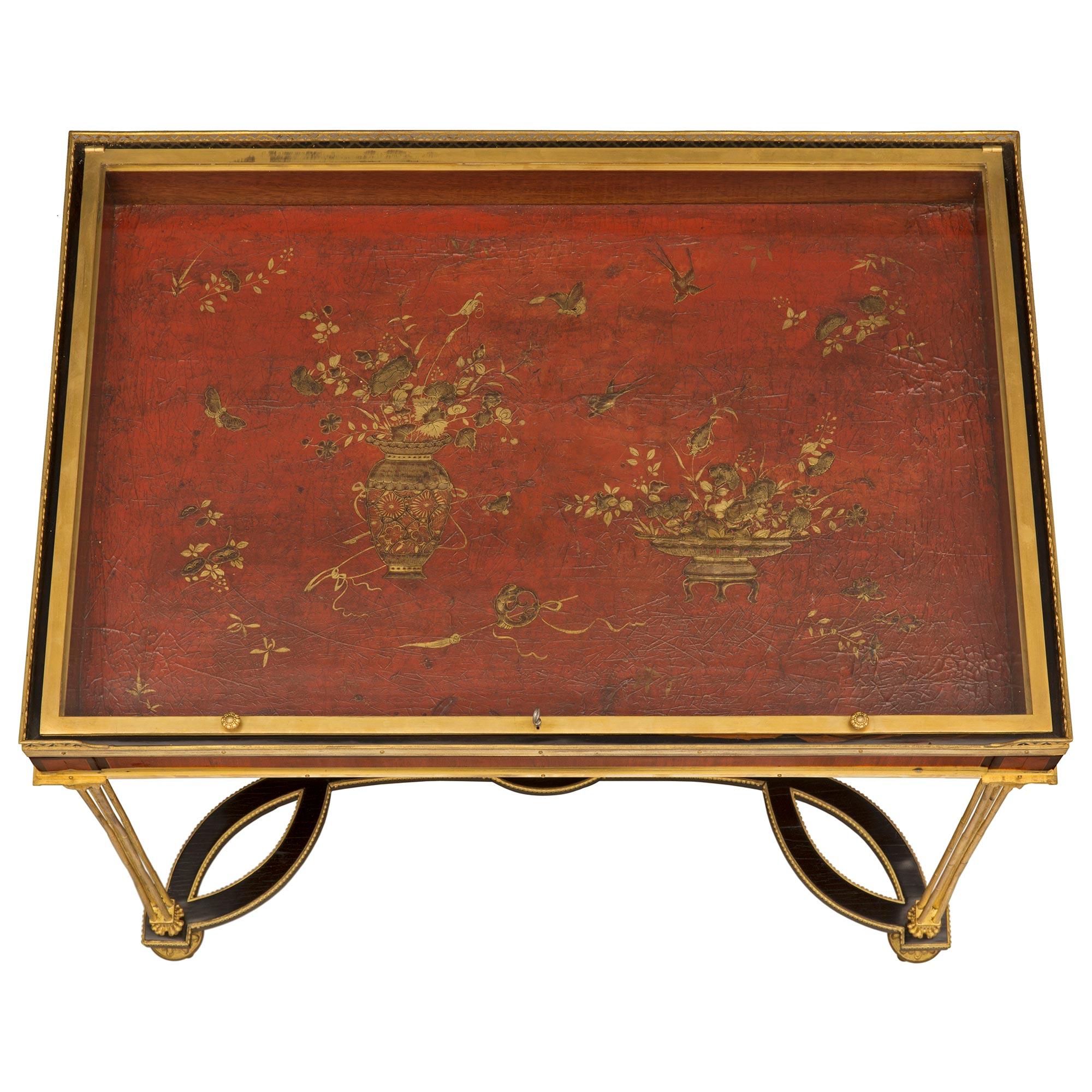 A spectacular and extremely high quality French mid 19th century Louis XVI st. Ebony, Kingwood, ormolu, and Japanese lacquer display table, after a model by Adam Weisweiler and attributed to Henry Dasson. The table is raised by most elegant topie