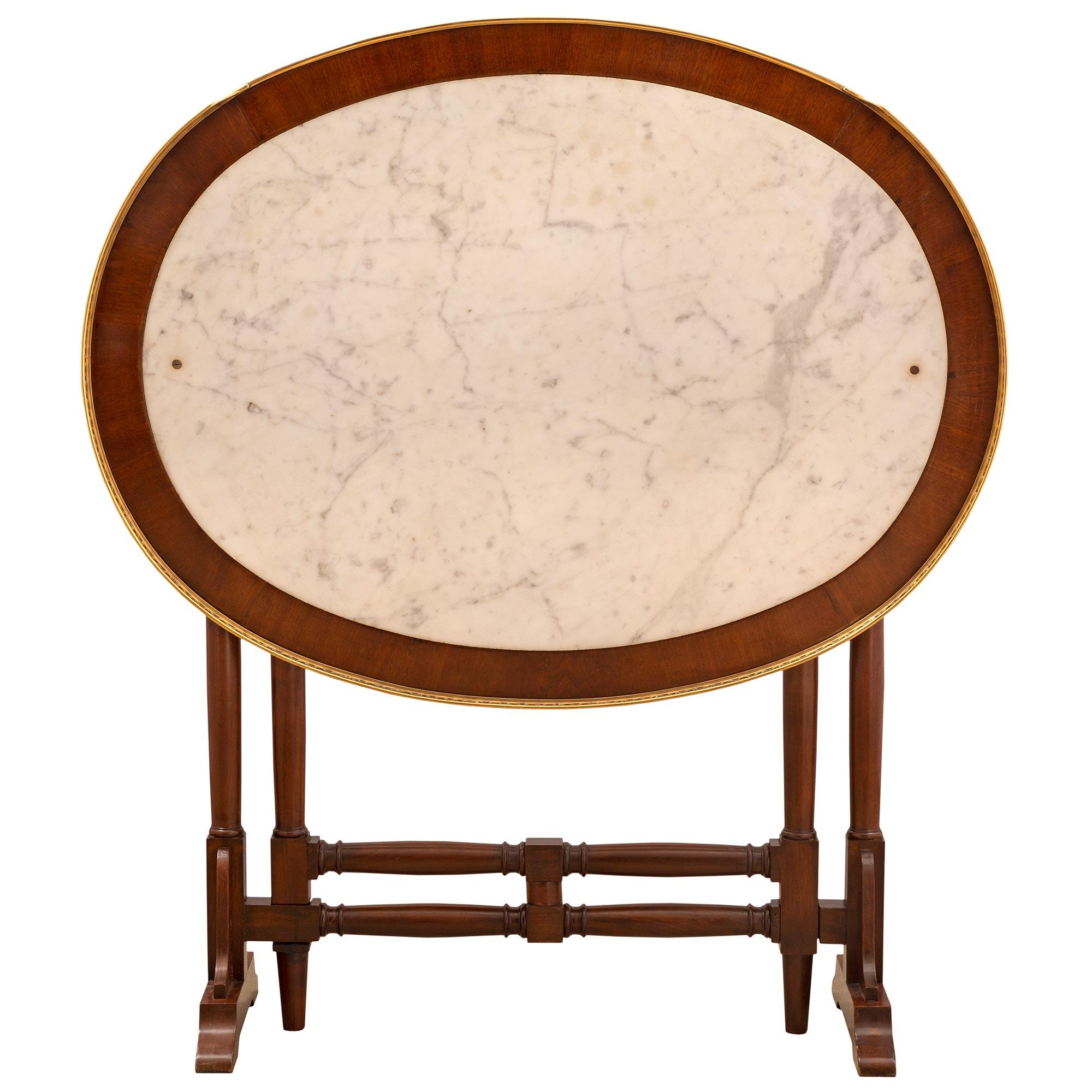 Élégante table à pieds de style Louis XVI en acajou, bronze doré et marbre blanc de Carrare. La table de forme ovale est surélevée par des pieds joliment tournés avec des supports arqués de chaque côté et des éléments élégamment courbés. Chaque