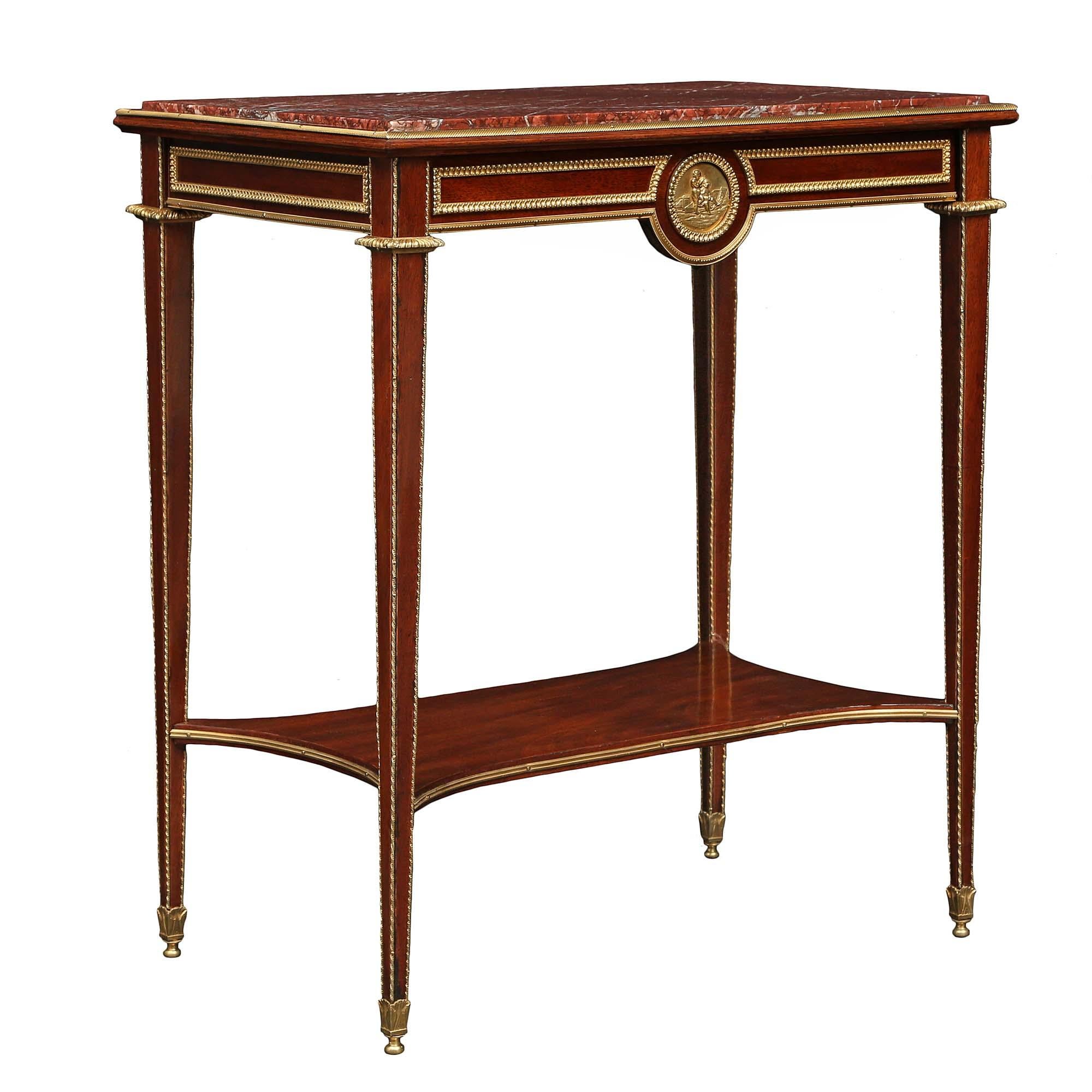 A very handsome French mid 19th century Louis XVI st. mahogany rectangular side table. The table is raised on slender tapered legs with twisted ormolu trim top mount and sabots. The legs are joined by a bottom tier with concave sides and ormolu