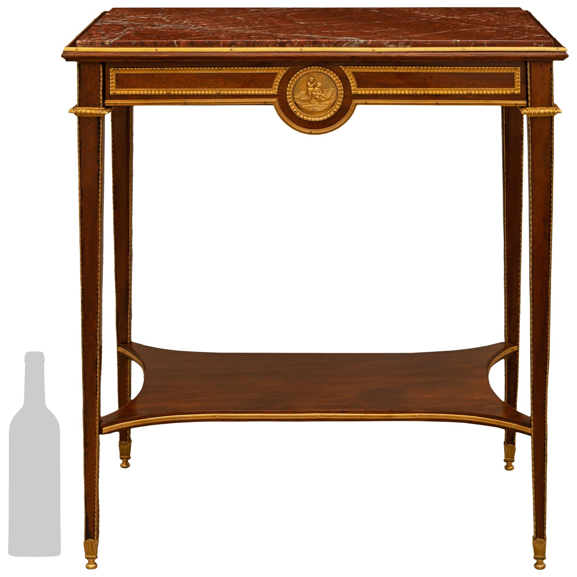 Très belle table d'appoint en acajou, bronze doré et marbre rouge de Catalogne, de style Louis XVI, du milieu du XIXe siècle. La table rectangulaire repose sur de minces pieds fuselés en acajou avec des garnitures torsadées en bronze doré, des