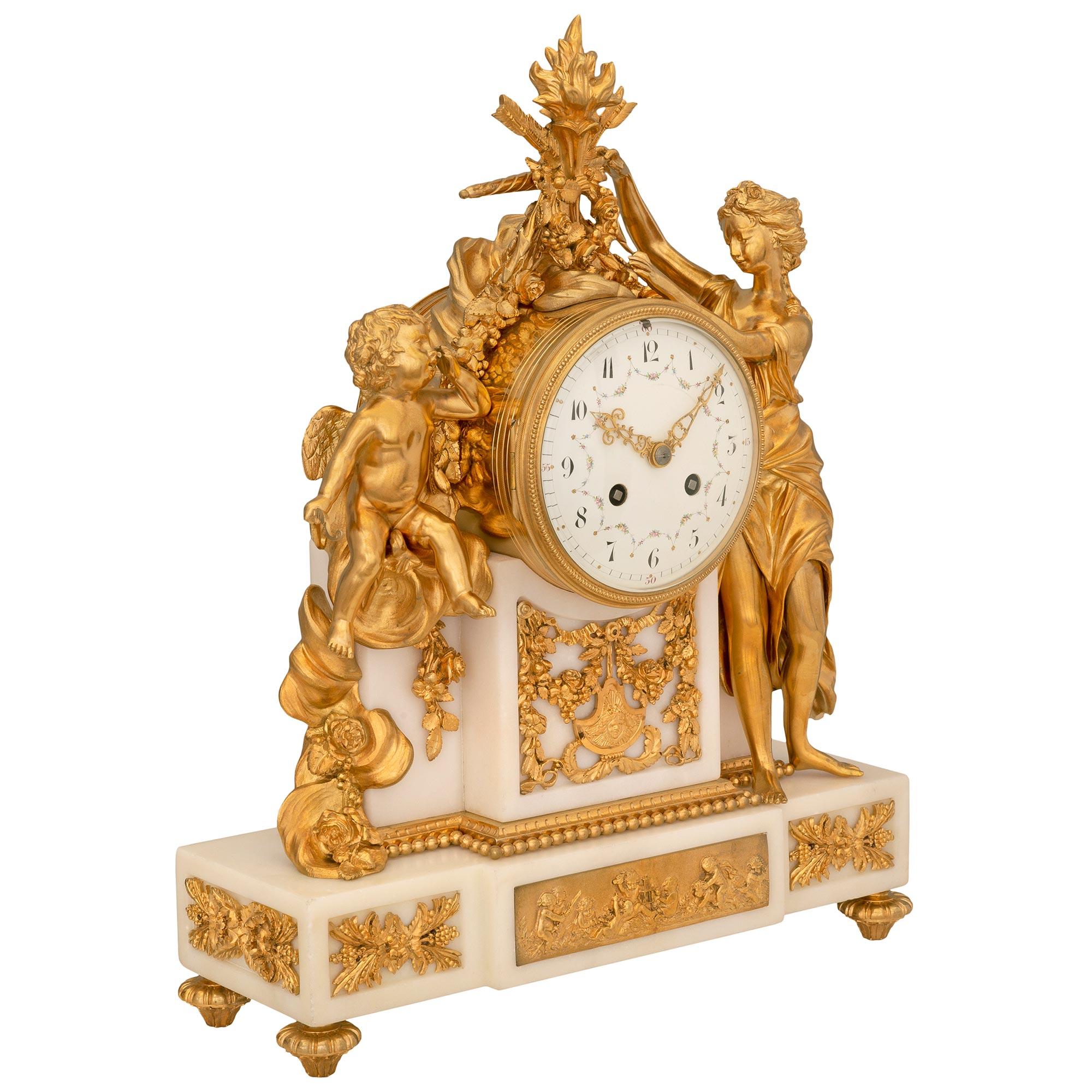 A spectacular French mid 19th century Louis XVI st. white Carrara marble and ormolu clock in the manner of Clodion. The clock is raised by elegant reeded topie shaped feet below the white Carrara marble base. The base displays a beautiful