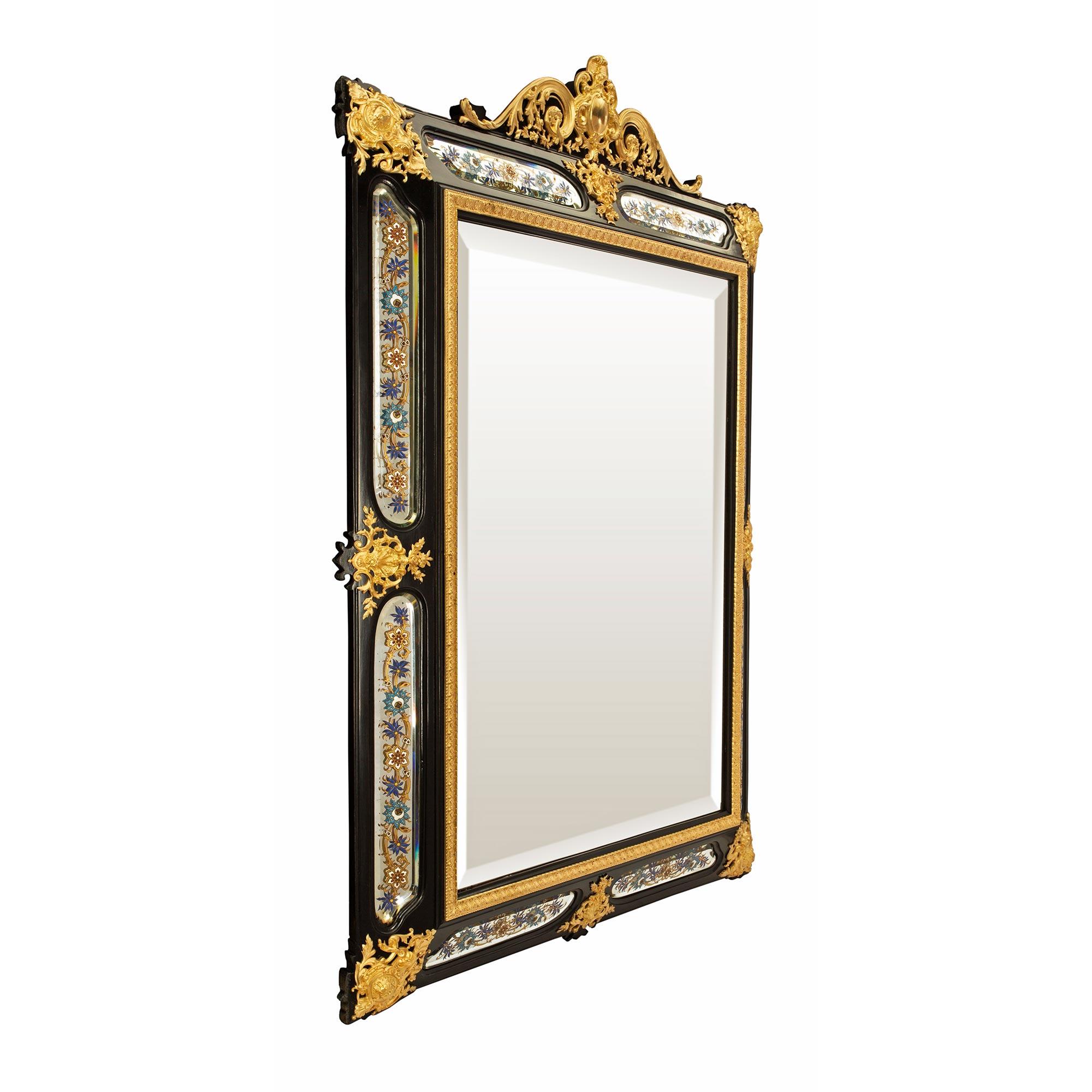 A stunning French mid 19th century Napoleon III period ebony and ormolu mirror. The ebony rectangular frame has beveled mirror inserts decorated by scrolled Églomisé floral designs, accented by richly chased ormolu mounts at each corner and sides.