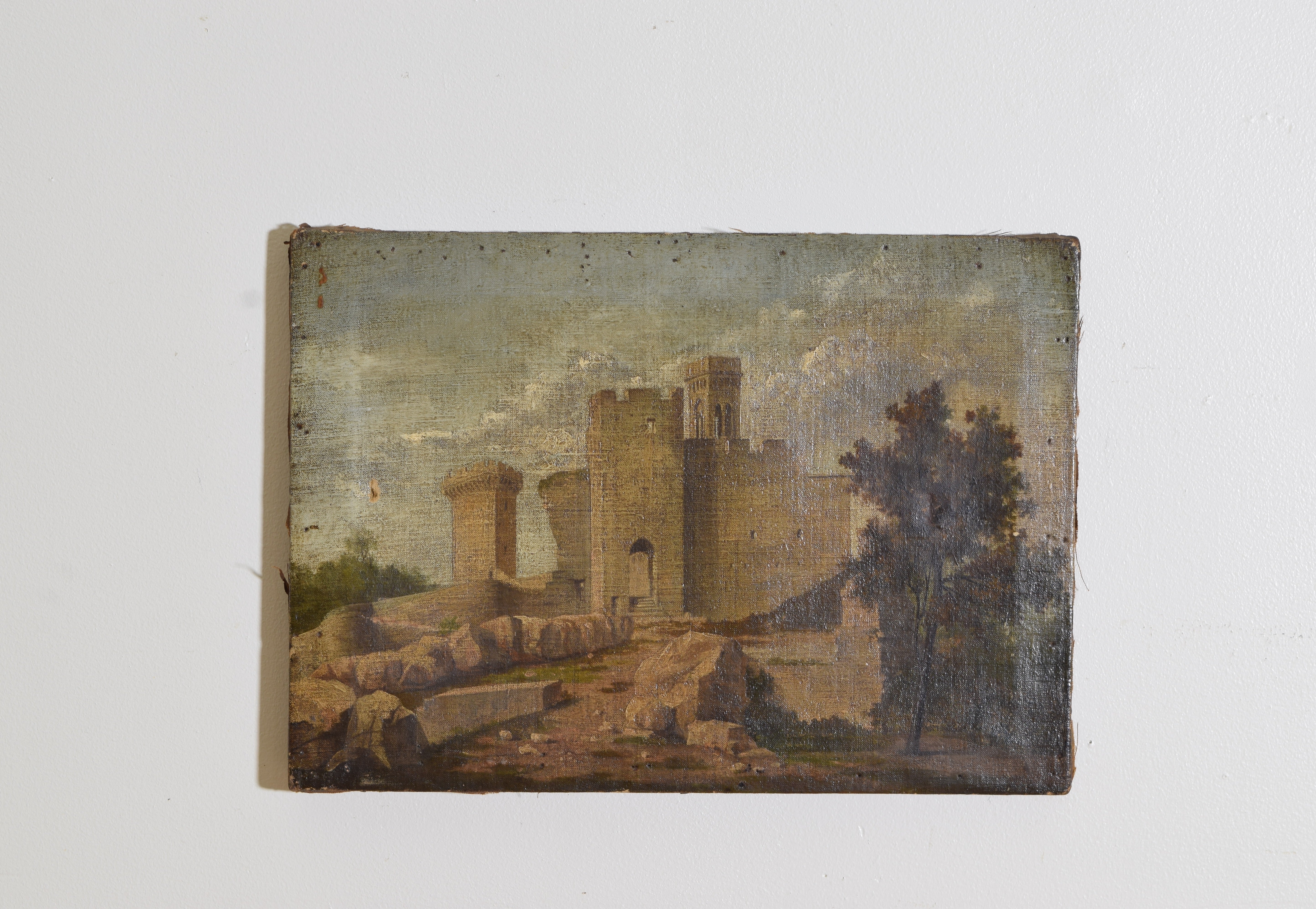 Depicting the boulder and rock strewn entrance to a castle with a tree in the right foreground, the castle with two parapets and a bell tower below a cloud filled sky, unframed 
