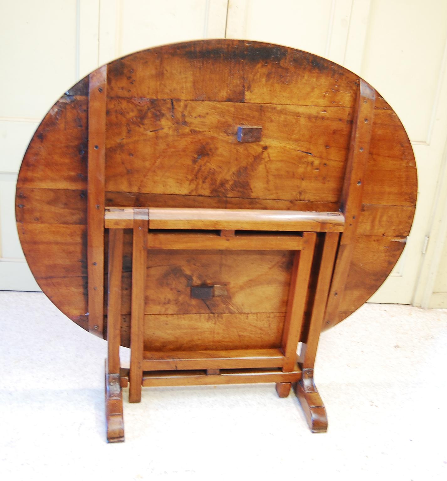 French solid walnut oval vendange table.  Vendange tables were traditionally used in the vineyards to set out lunch for the workers during the 
 growing and harvest seasons.  They tilt up so they take up very little room in the wagon that would