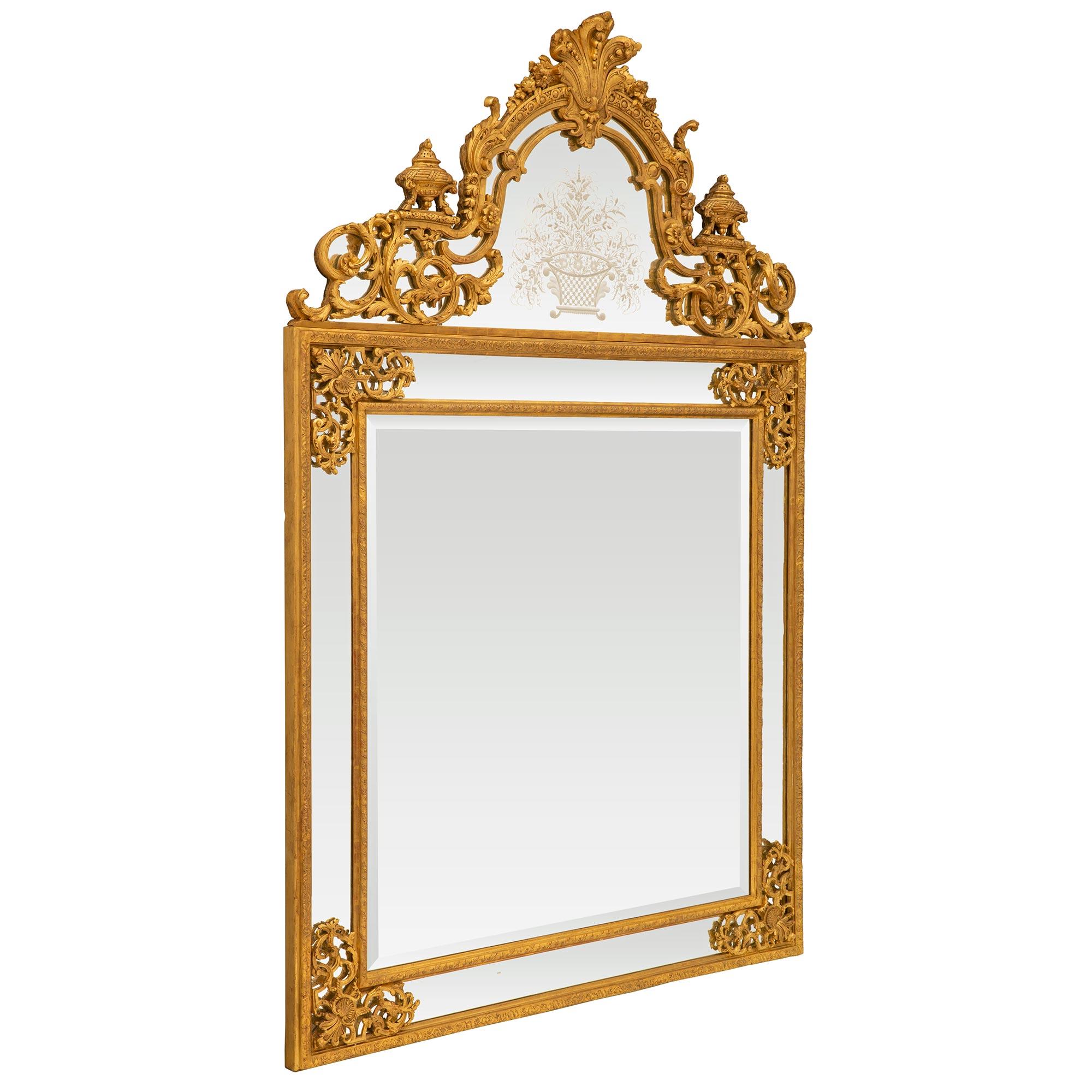 A stunning large scale French Mid-19th Century Regence St. Double framed giltwood mirror. The mirror retains all original beveled and etched mirror plates throughout each framed within Fine mottled bands with charming richly carved scrolled foliate