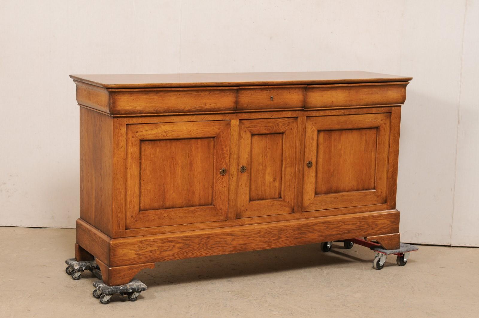 A French wooden buffet cabinet from the mid 20th century. This vintage fruitwood cabinet from France, just over 6 feet in length, features a rectangular-shaped top with softly molded edge, above a case which houses three drawers set horizontally at