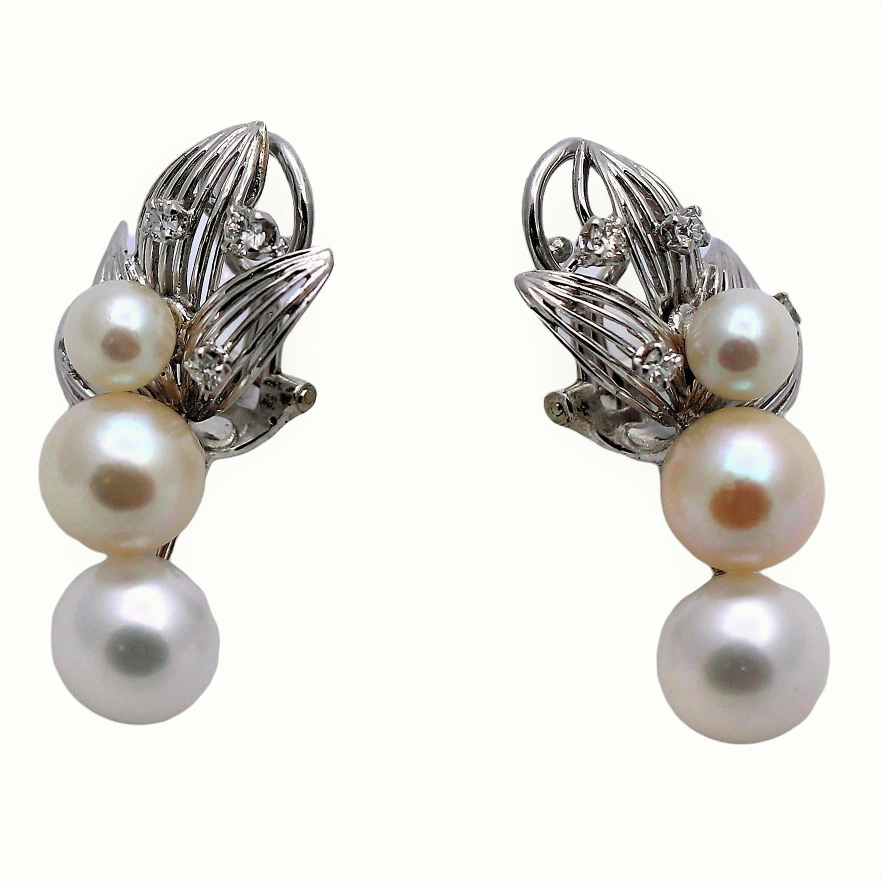 The earring tops are a delicate open wire work of 18K white gold petals, set with eight fine quality single cut diamonds, having a total approximate weight of .33ct. From this motif drop three Akoya cultured pearls, graduating from 6mm to 9mm. Each
