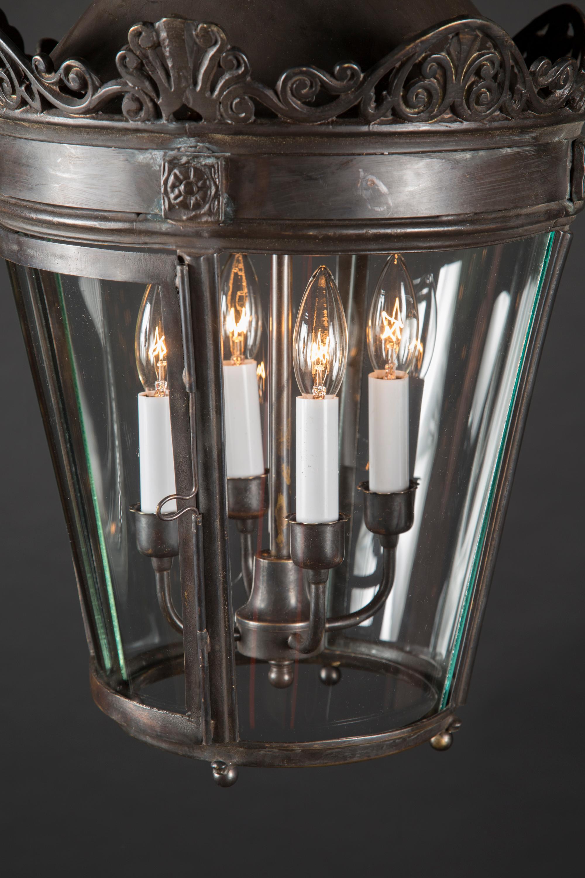 This unique bronze oscuro finish lantern features curved glasses and a detailed turret at top. The turret is reminiscent of the street lights which once stood tall on the streets of Paris, some of which were later converted to hanging lanterns like