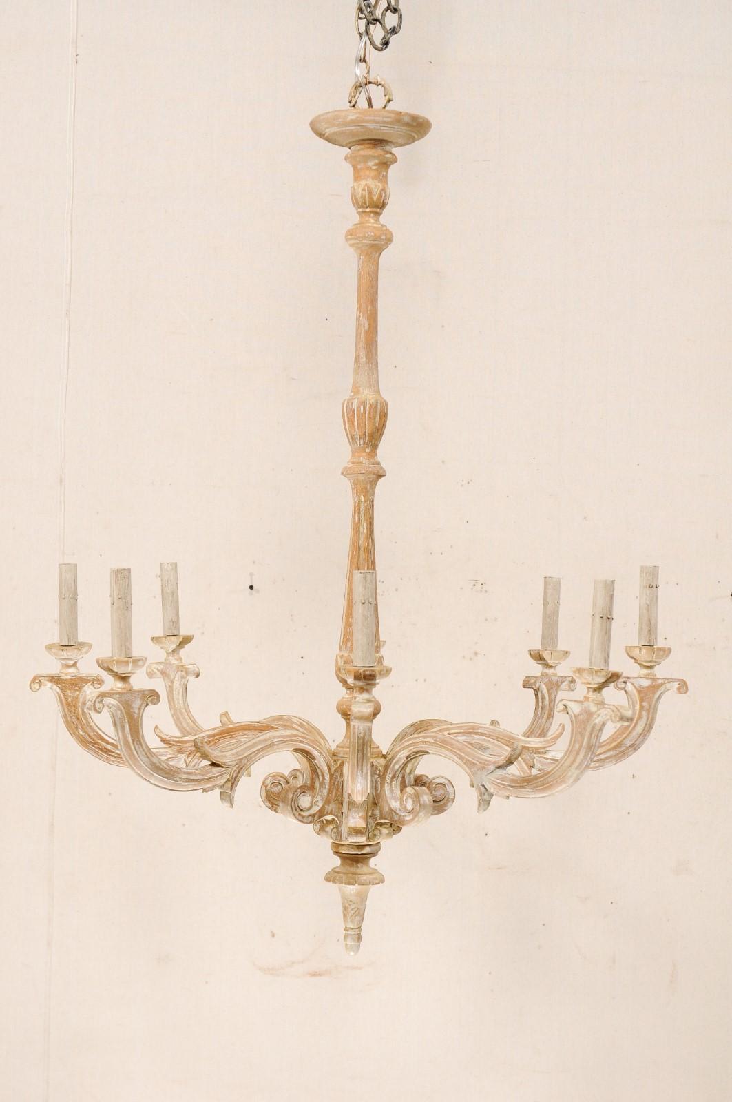 A French eight-light carved wood chandelier with elongated central column. This French mid-20th century chandelier features a long central wood column, with carved with fluting and wrapped foliage motif, terminating into a carved bottom final. The