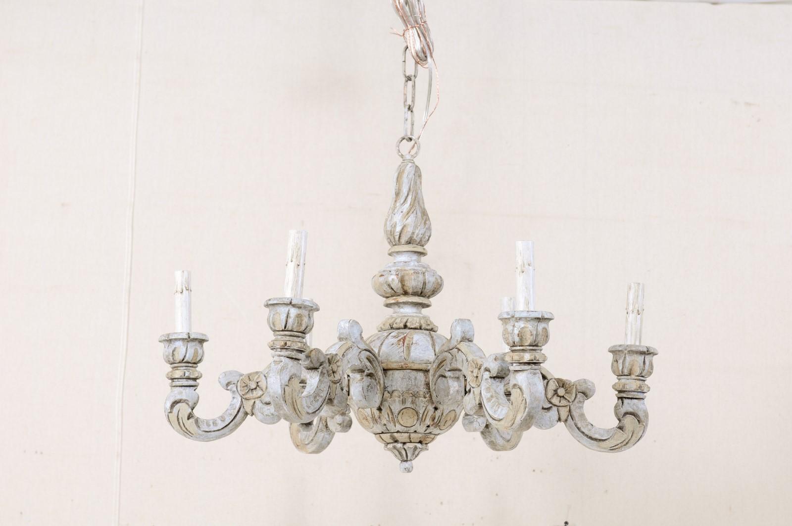 A French mid-20th century carved wood six-light chandelier. This lovely vintage chandelier from France features a curvaceous central column, with small medallions, leaf, and fluted motifs, a sphere-shaped gallery, and sweetly carved bottom finial