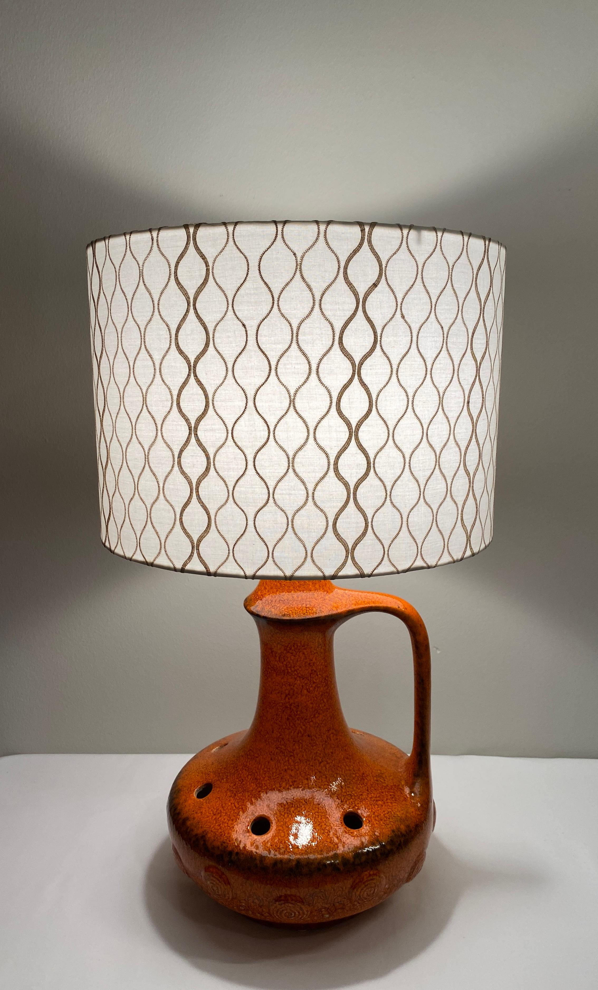 Une grande lampe de table très décorative du milieu du siècle en céramique émaillée orange brûlé avec de légères nuances de brun. Pièce en céramique fabriquée à la main et originaire de Vallauris, en France. Fabriquées à la manière des lampes de