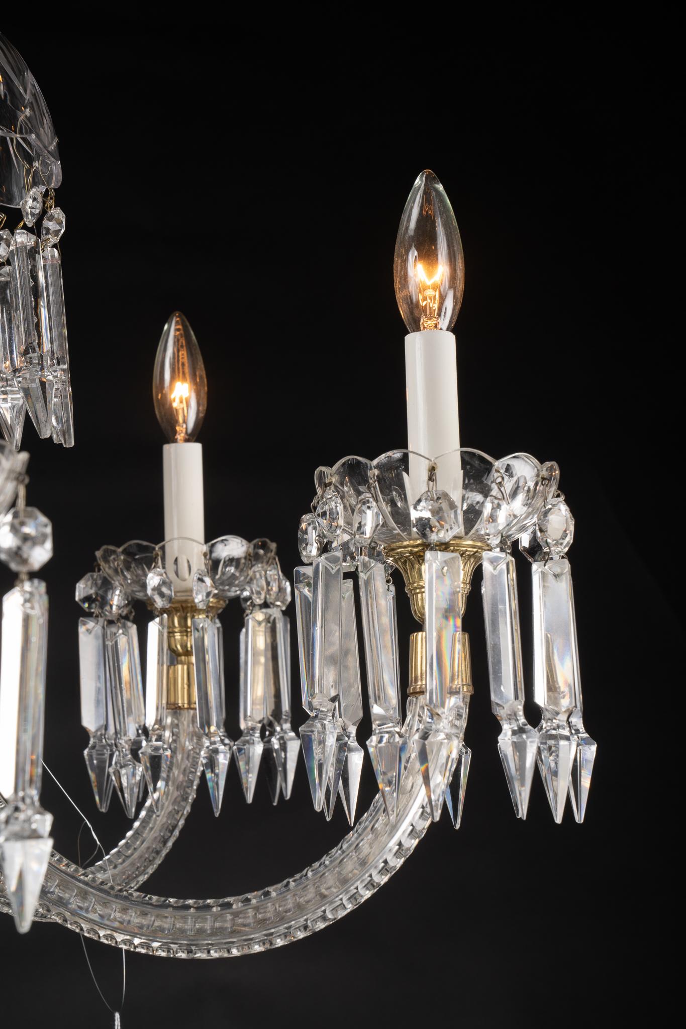 This French crystal chandelier dates back to the mid 20th century and offers a unique design. At top we see a crown of scrolling crystal. Moving down the central stem we meet a beautiful and simply patterned crystal bowl from which the six crystal