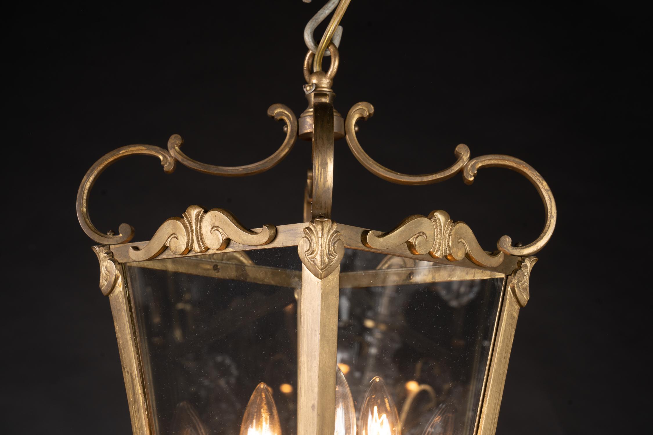 This beautiful and simple bronze lantern features glass panes and is suspended by four scrolling arms. The French fixture dates back to the mid 20th century and plays host three lights.