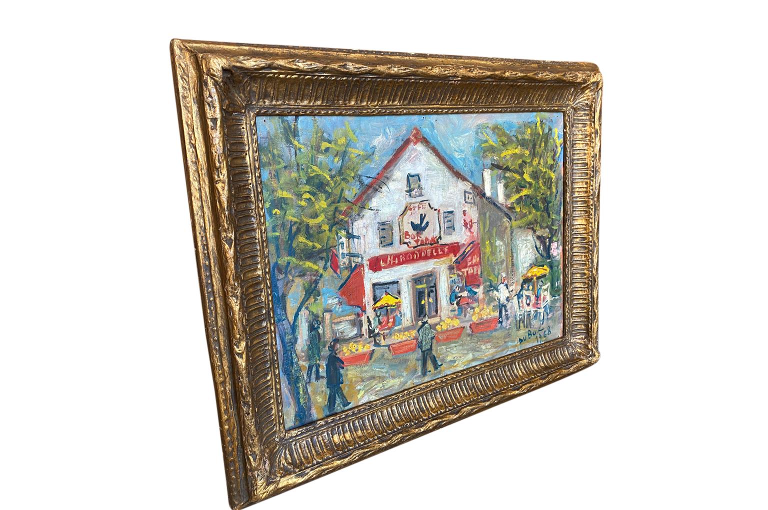 A very delighted oil on canvas painting by Roland Dubuc (1924 - 1998). A charming scene of the Cafe Bar Tabac - L'Irrondelle - Cafe The Swallow. Lively bright colors and wonderful brushwork. Housed in a stunning frame made from papier mache.