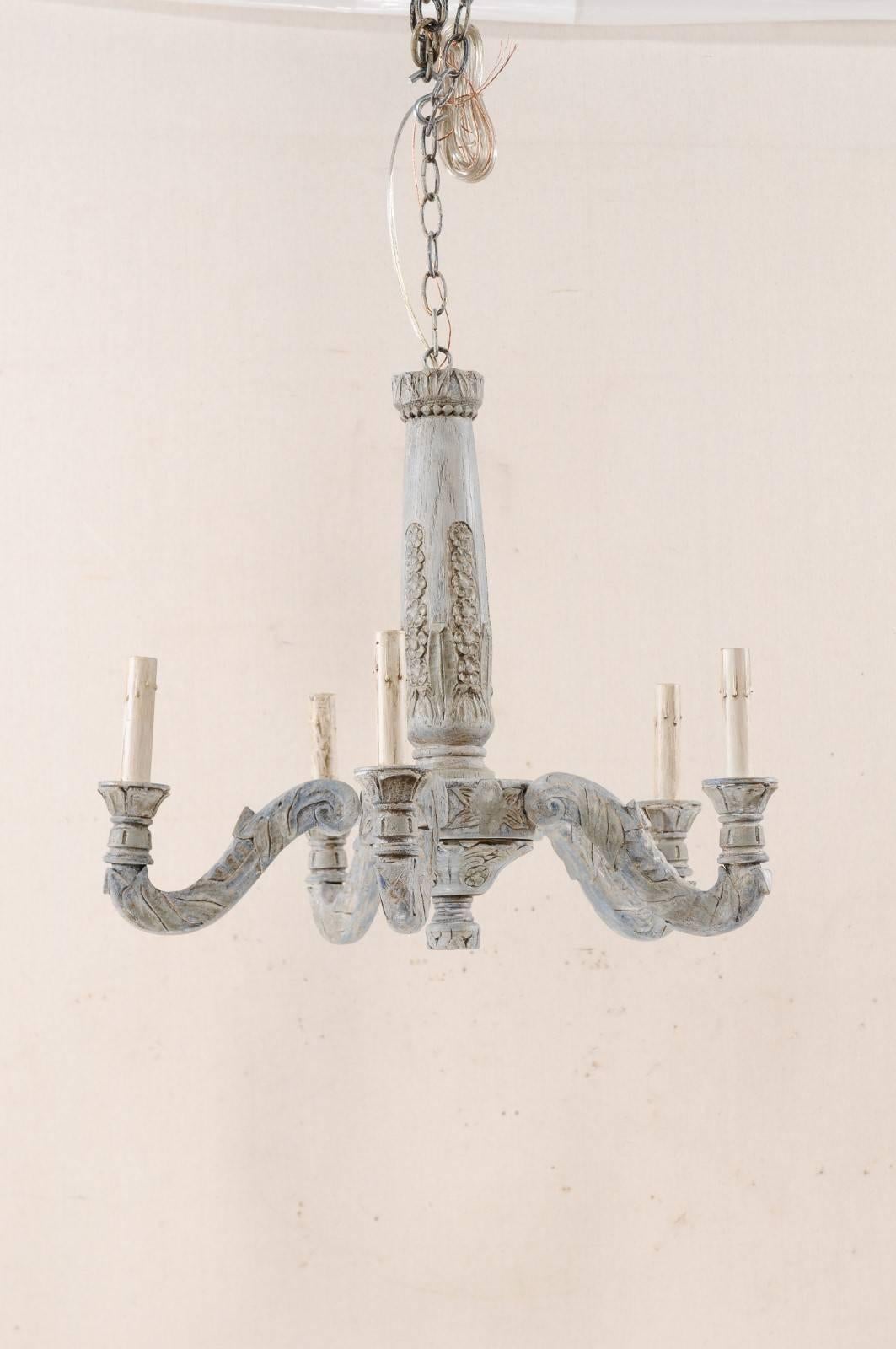 A French mid-20th century carved and painted wood five-light chandelier. This lovely French chandelier from the mid-20th century features a carved central column in delicate flower and foliage motif with five s-scrolled arms emerging outward that