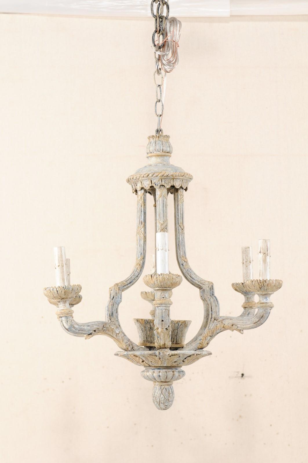 A French six-light painted and carved wood chandelier from the mid-20th century. This vintage chandelier from France features a nicely carved upper canopy which sits atop an airy, lantern-style carved central gallery with column and leafed basket