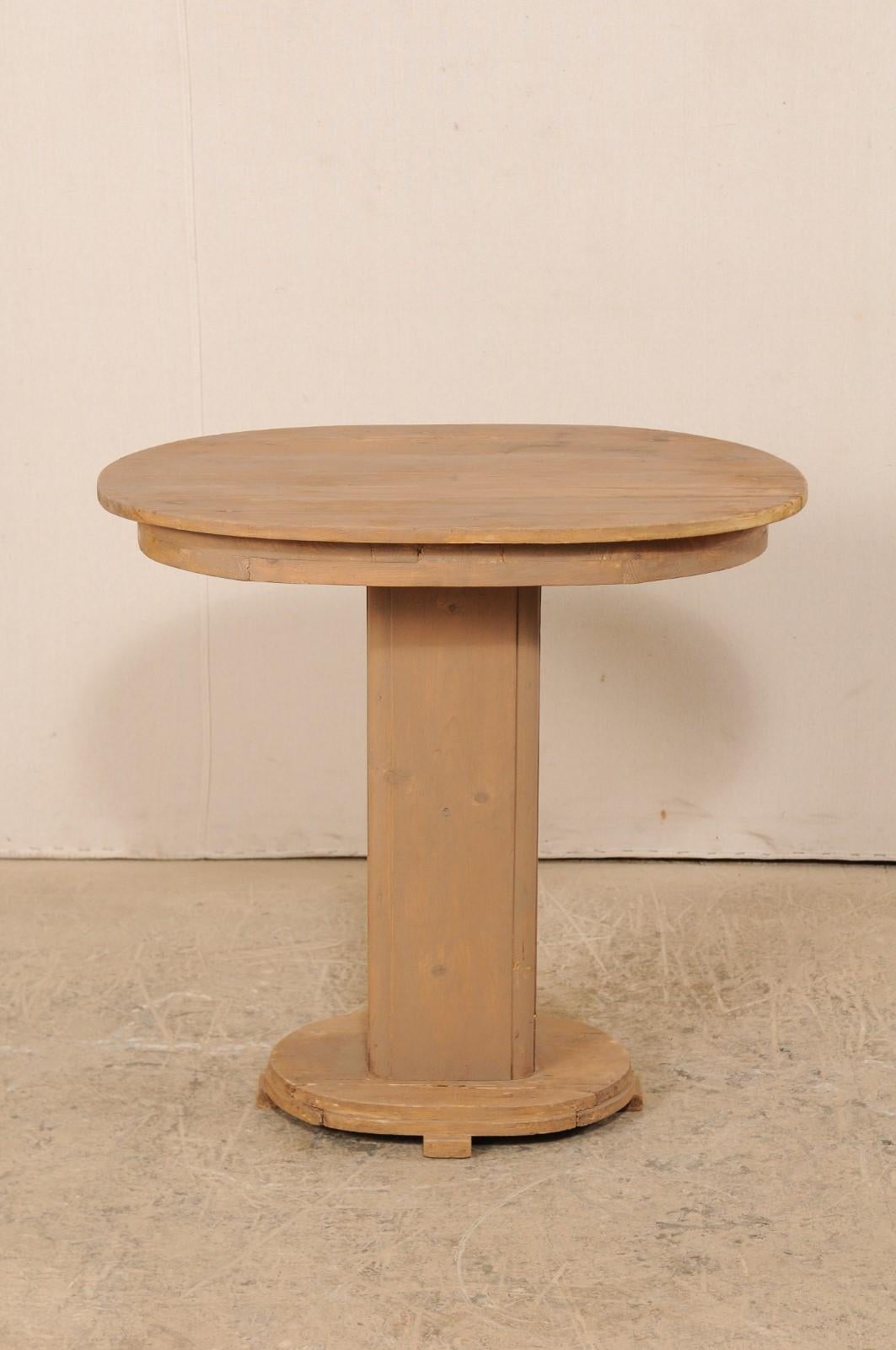A French painted wood oval-top pedestal table from the mid-20th century. This vintage table from France, features a oval-shaped top with plain skirt, which rests atop a rectangular-shaped column with rounded edges, and a smaller oval-shaped base.
