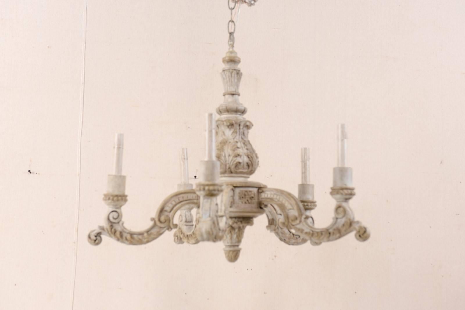 A French mid-20th century carved wood six-light chandelier. This lovely French chandelier from the mid-20th century features a curvaceously carved central column in acanthus leaf motif, with six scrolled arms emerging outward that are each adorned