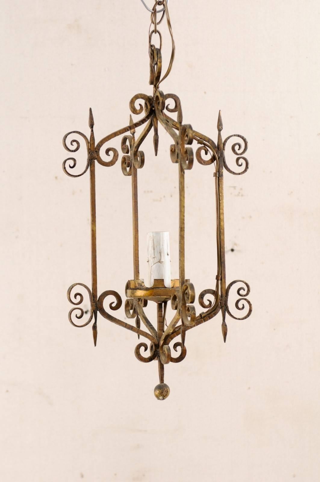 A French single light iron chandelier from the mid-20th century. This vintage French chandelier features a delightful iron-shaped body adorn in scrolled accents, and a small balled bottom finial. There is a nicely sized single light, with painted