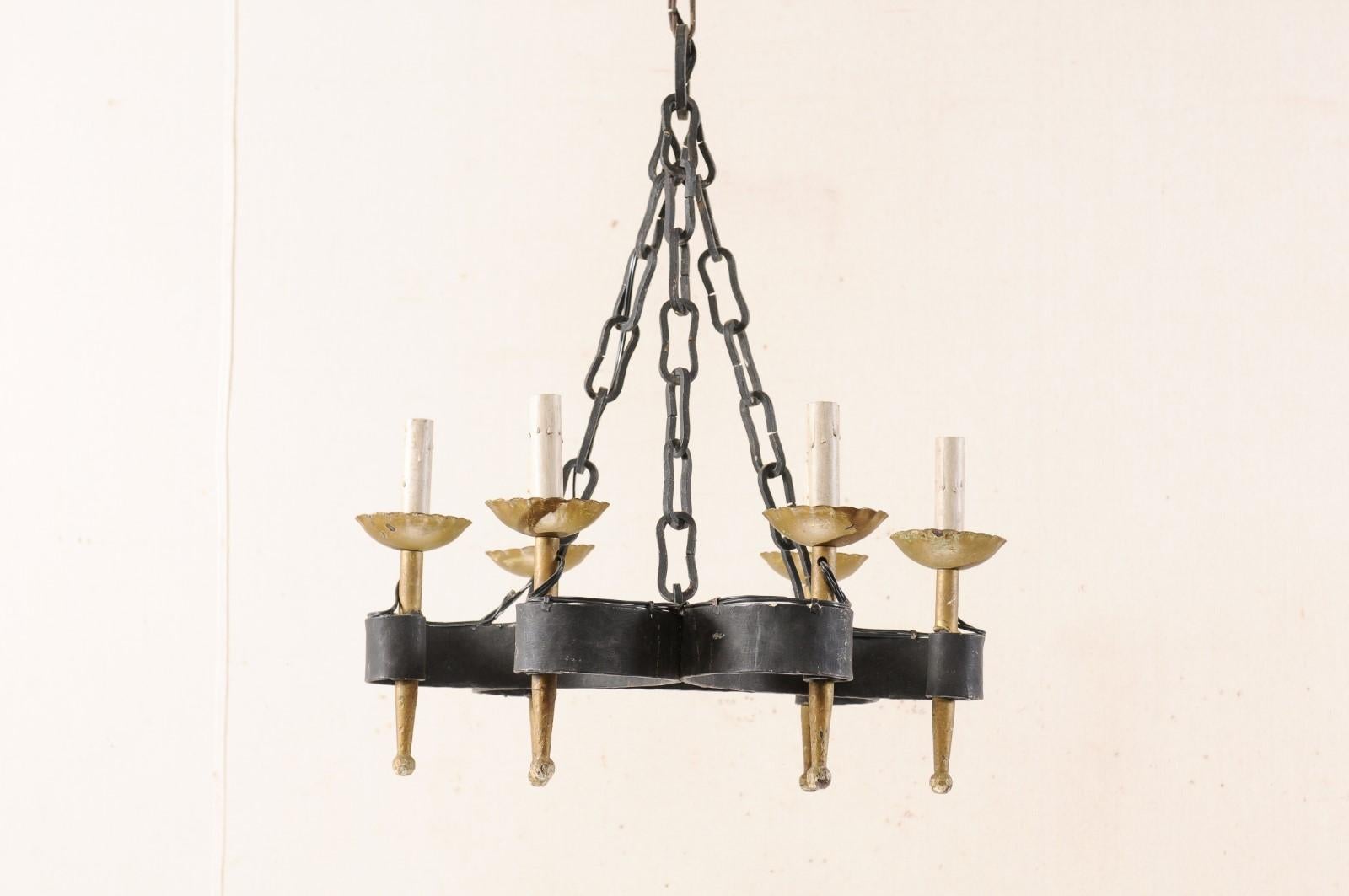 A French six-light iron chandelier from the mid-20th century. This vintage French hand forged iron chandelier features a central gallery comprised of three wide-banded and connected C-shaped scrolls. The six torch-style golden bronze toned arms are