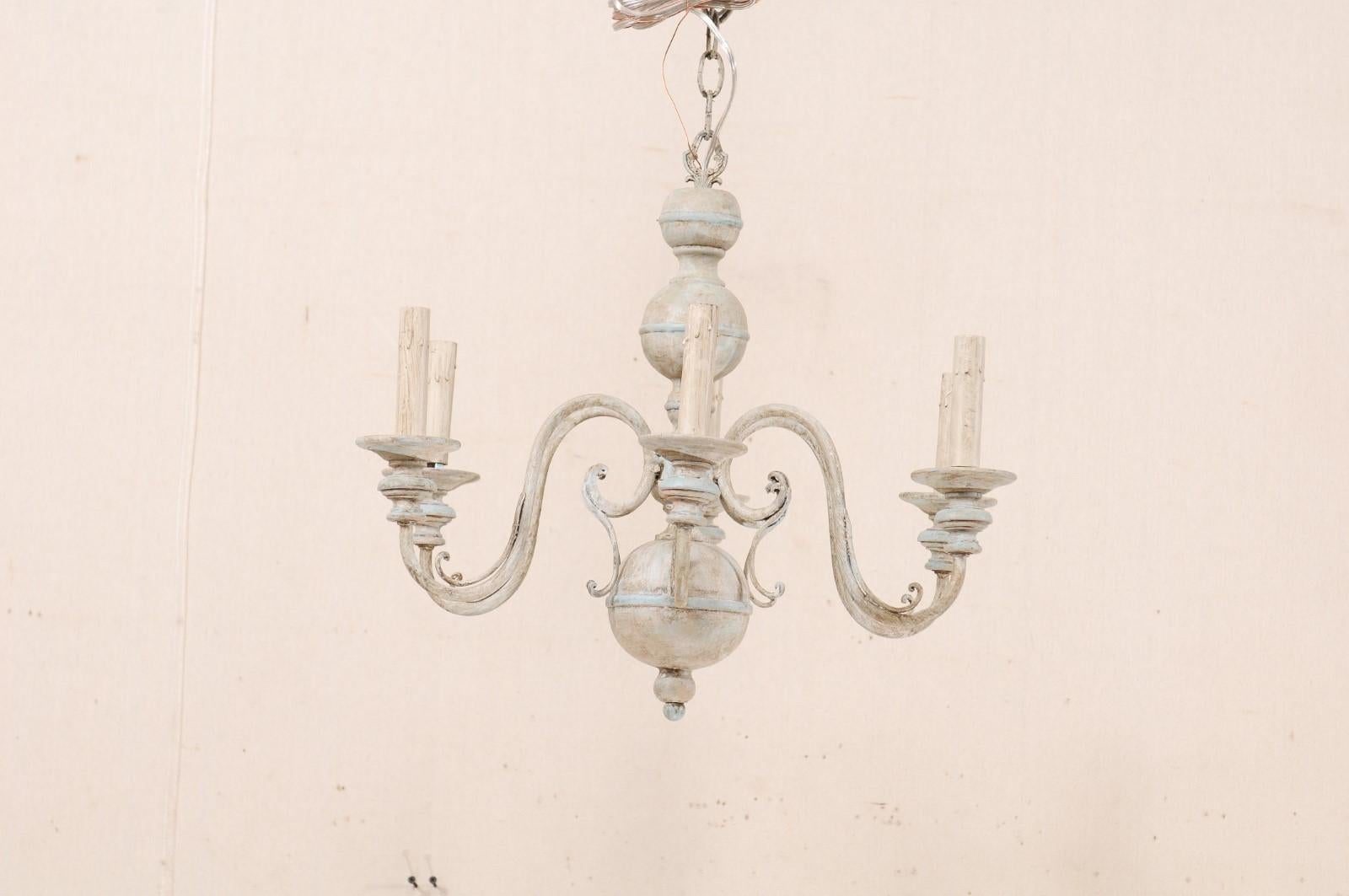 A French six-light painted wood and metal chandelier. This lovely mid-20th century French chandelier features a carved wood column with fluid s-shaped swooping arms lifting up and out from it's centre. This column features a serious of bulbous