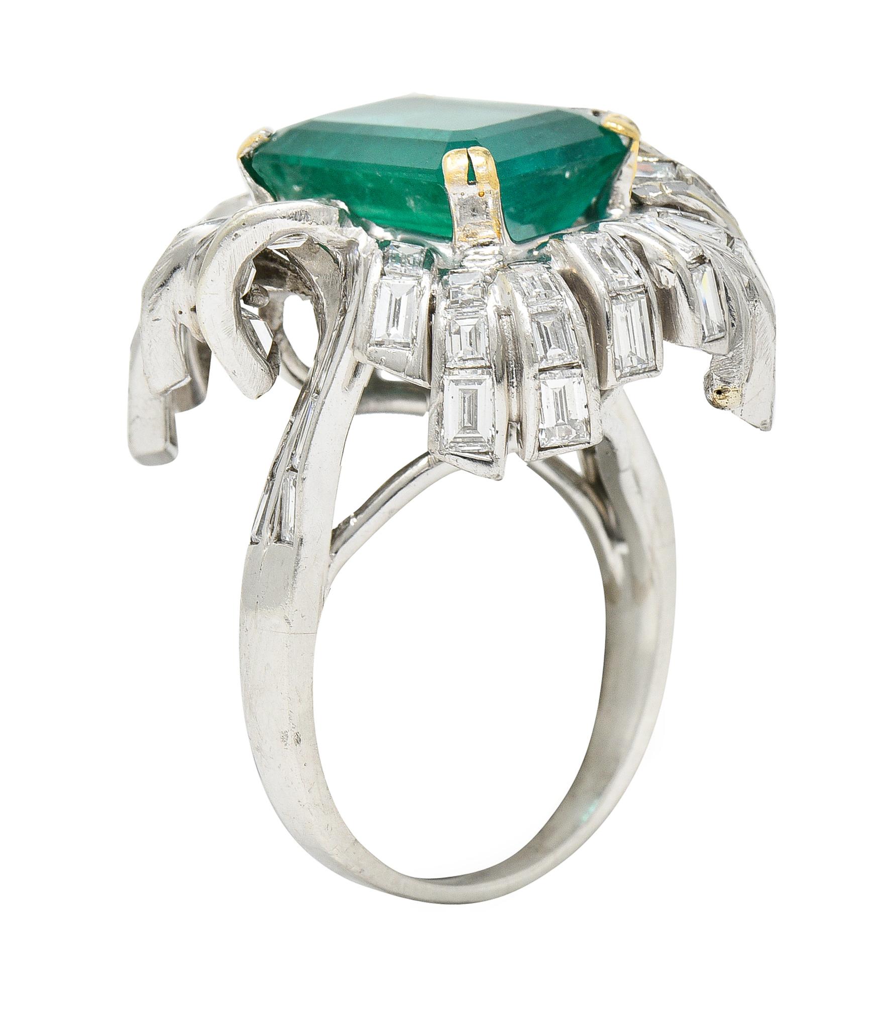 Cluster style cocktail ring centers an emerald cut emerald weighing approximately 6.65 carats

Strongly bluish green in color and translucent with natural inclusions

Set by gold prongs then surrounded by undulating channel set tendrils featuring